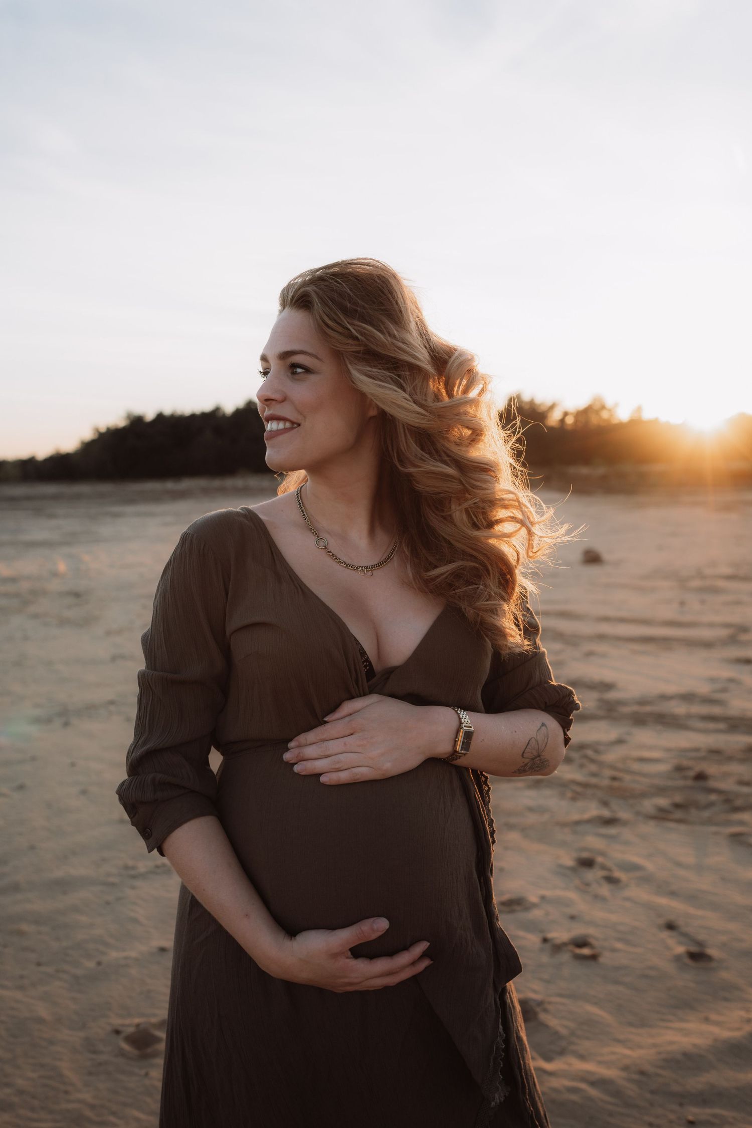 Sunset beach maternity session with flowing hair and brown dress.