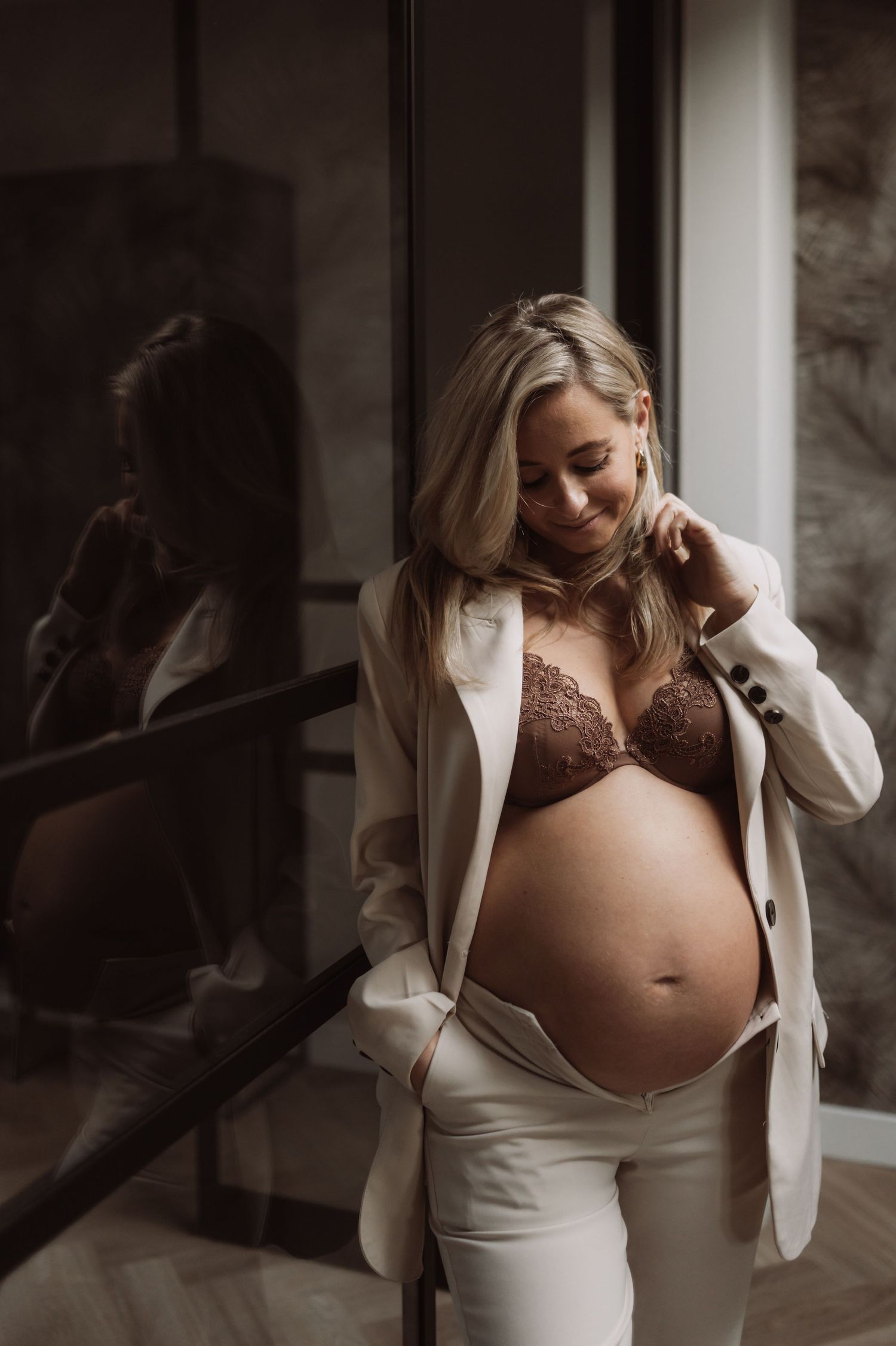 Intimate maternity boudoir photo with white cardigan and lace undergarments.