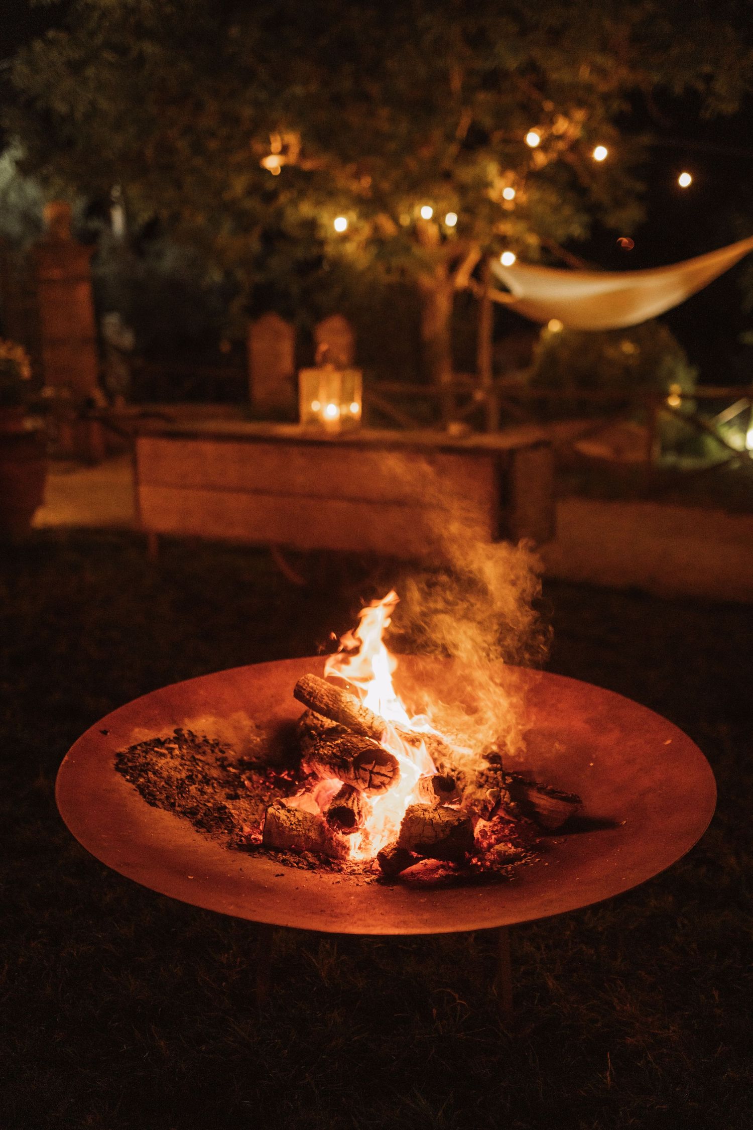 A sequence of images showing a fire pit glowing at night with string lights in the background creating an ambient atmosphere.