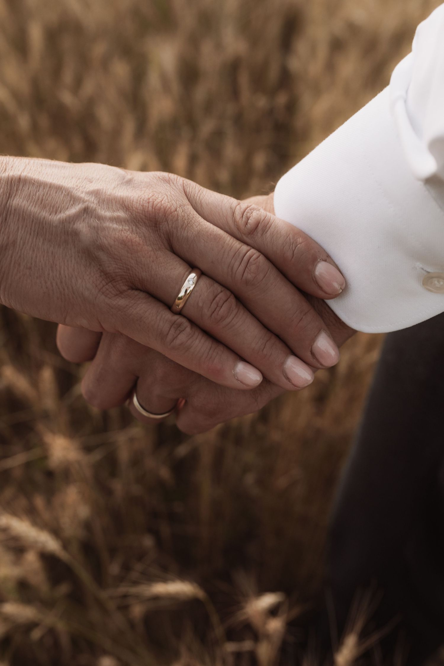 Close-up shot of hands exchanging a white envelope against a brown blurred background.