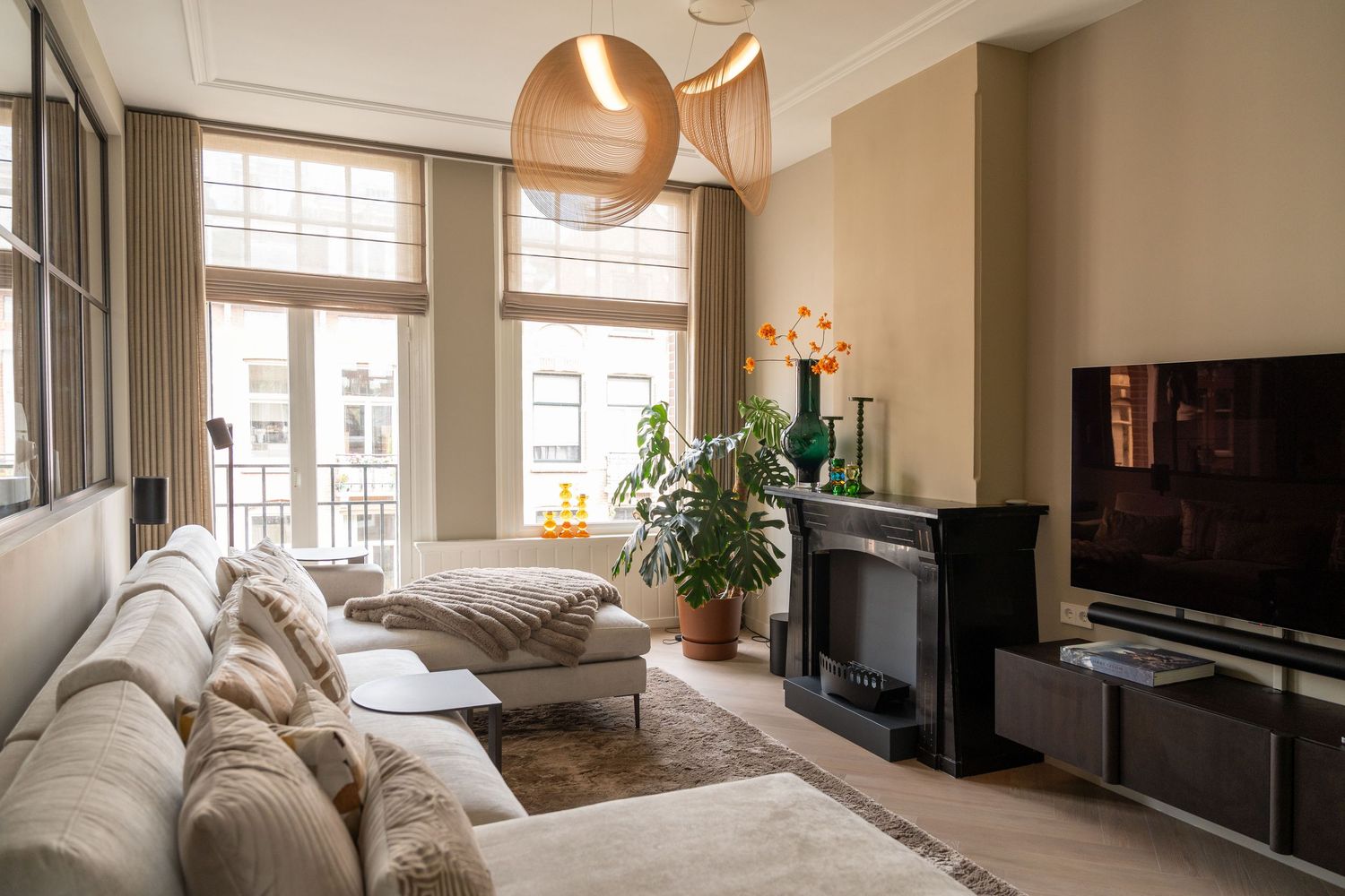 A modern living room with floor-to-ceiling windows, neutral decor, and a plush sectional sofa in a bright space.