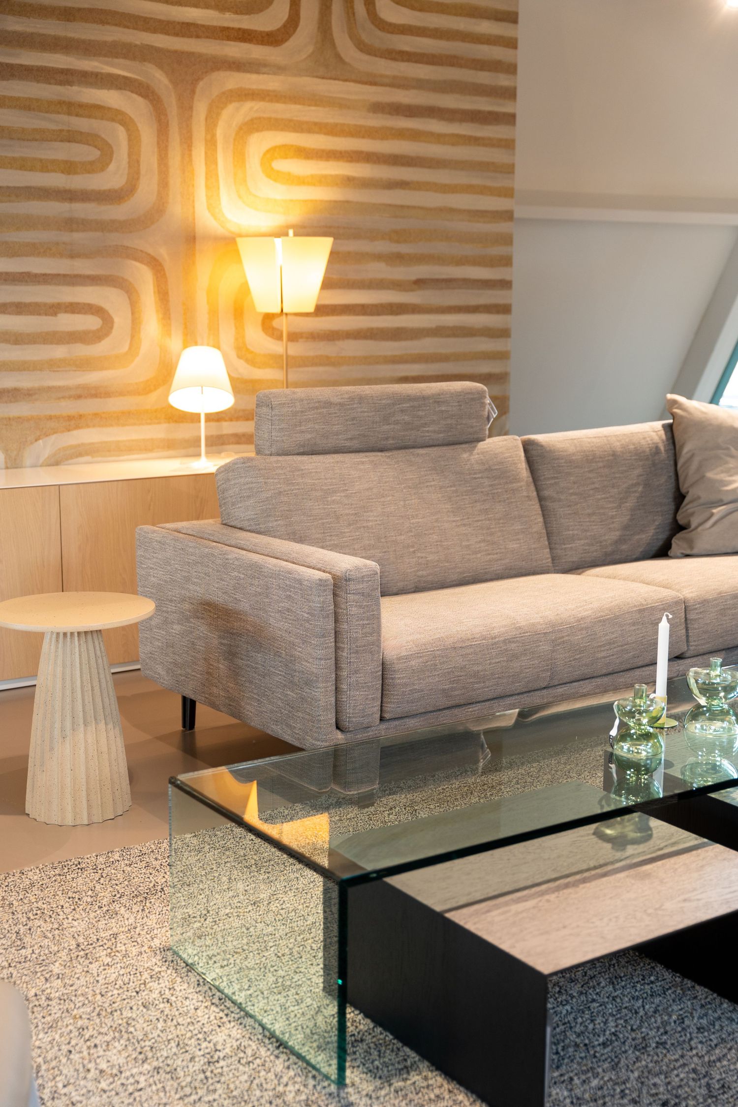 Modern living room with gray sofa, glass coffee table, and striped accent wall design.