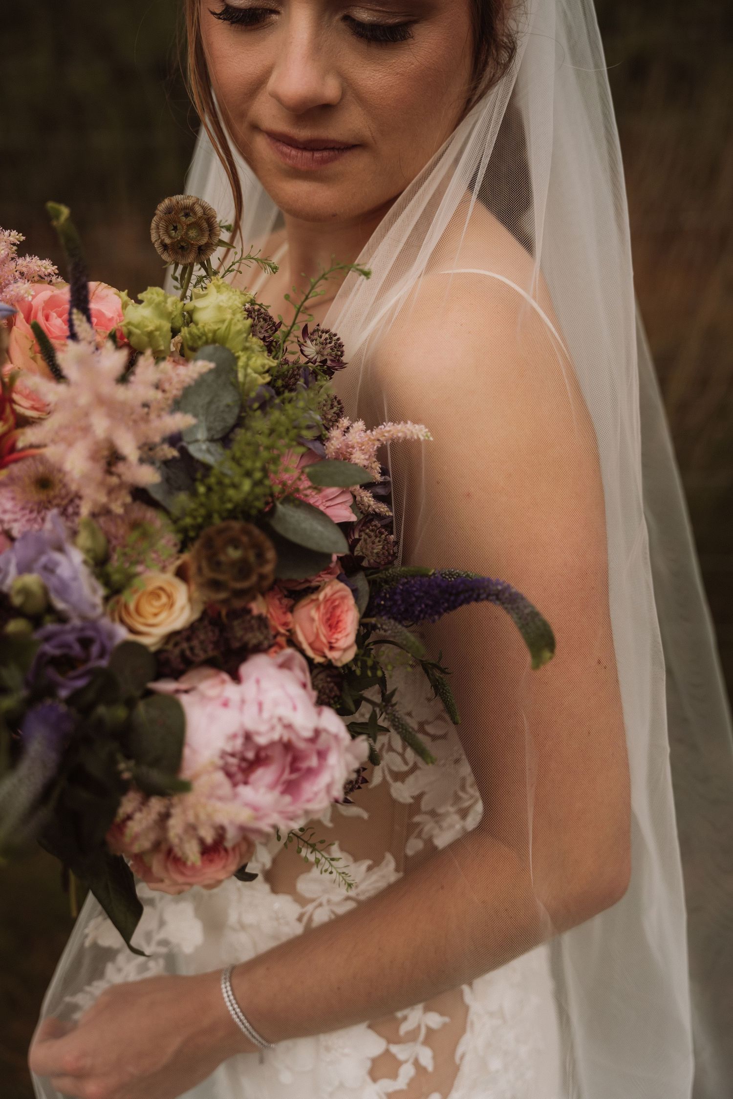 Elegant bridal portrait showing delicate lace details and a colorful floral bouquet.