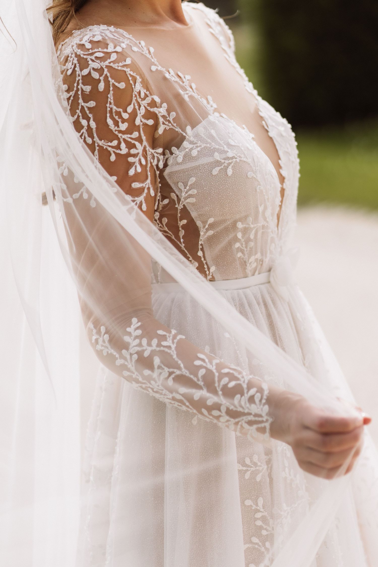 Detailed shot of delicate lace sleeves and bodice of a wedding dress.
