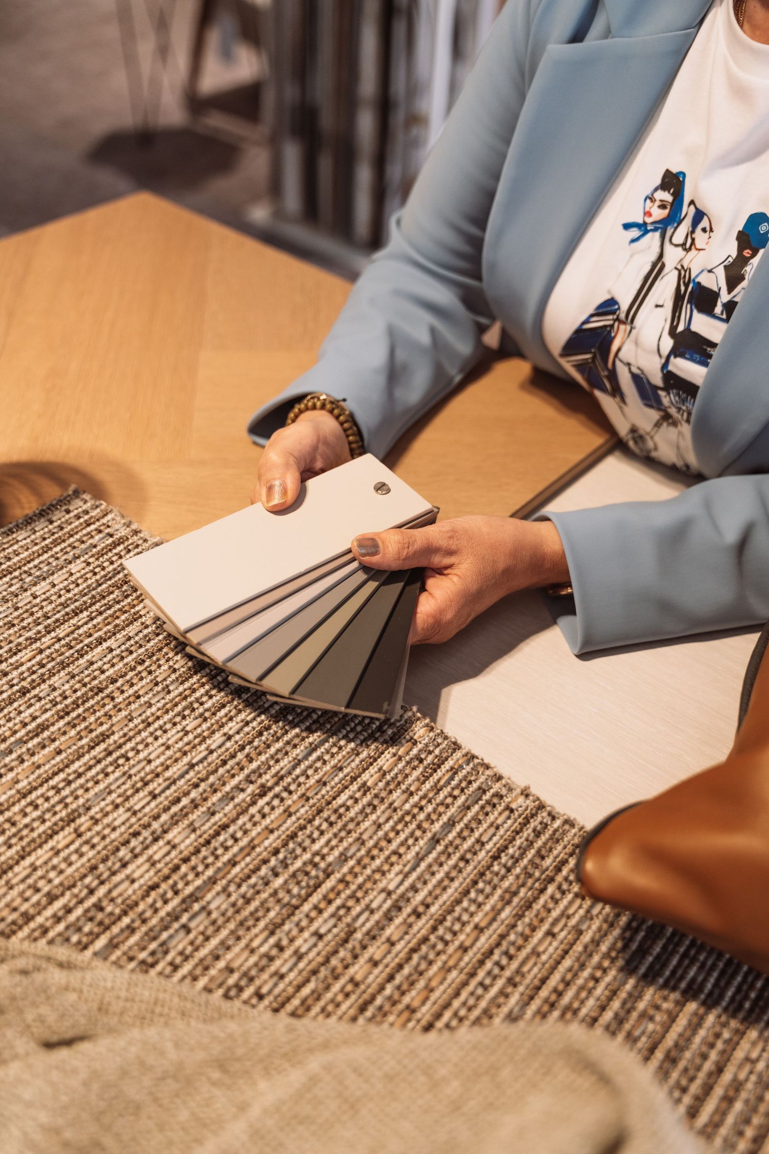 Professional in a blue blazer reviews fabric swatches and material samples on a textured surface.