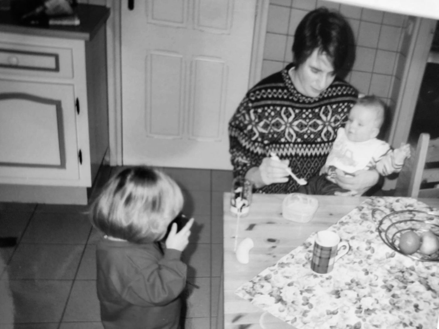 Black and white photo of children playing at a dining table.
