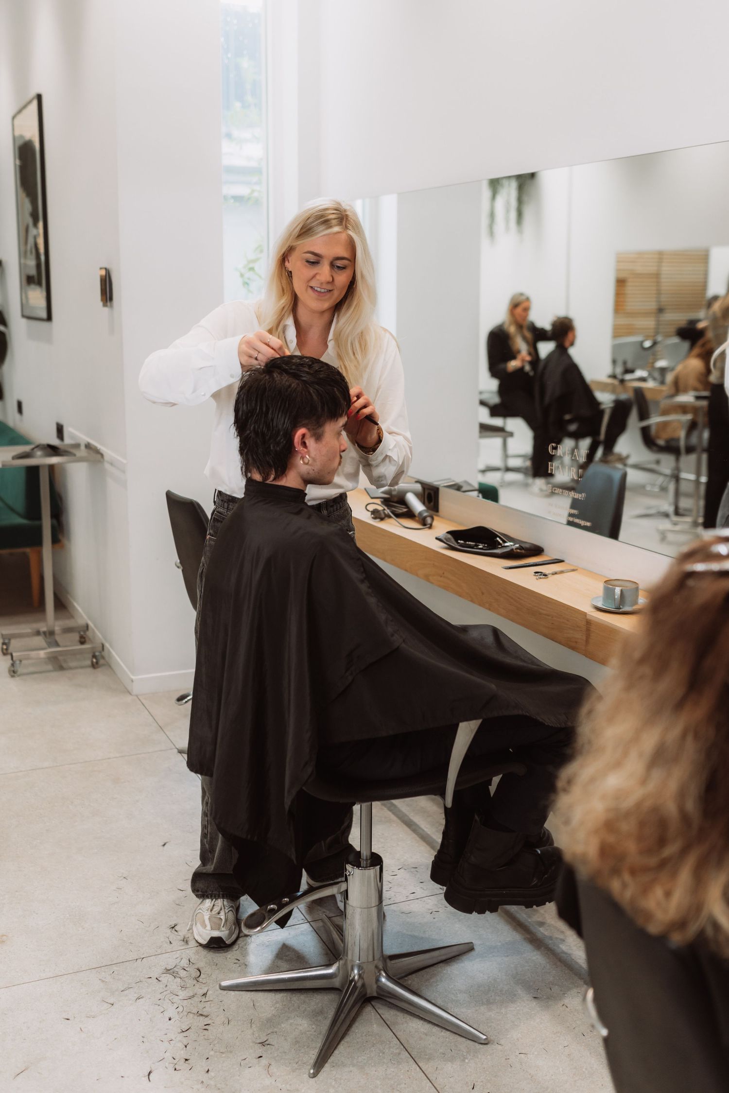 Hair salon professional providing styling service in modern white salon interior.