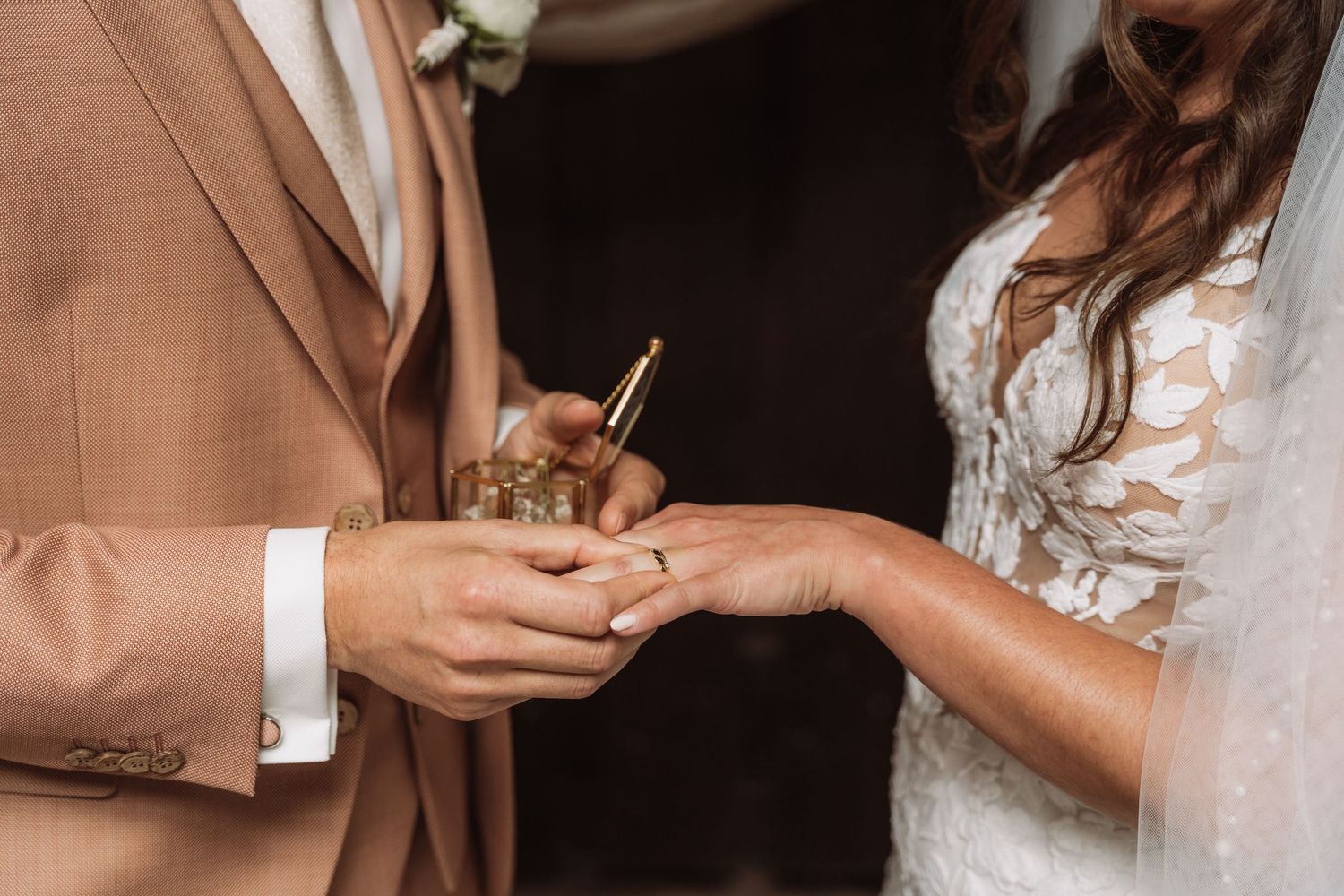 Close-up shot of hands exchanging wedding rings during an intimate ceremony.