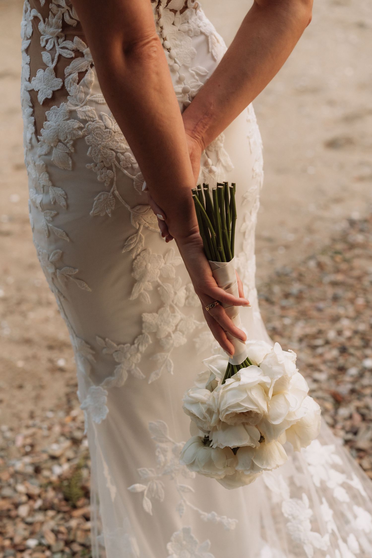 Close-up view of hands holding a white floral bouquet against a textured background.