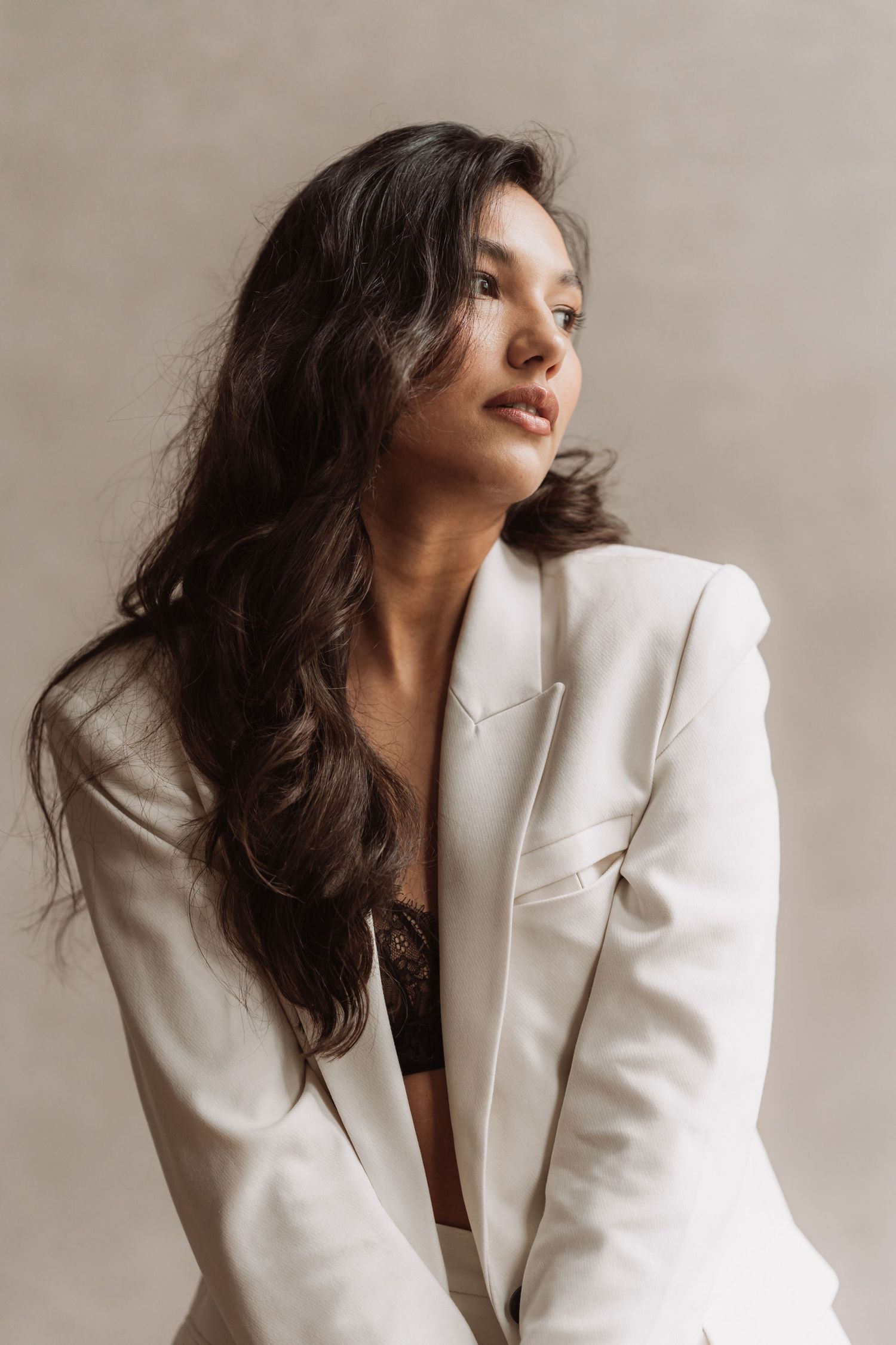 Fashion portrait of a model in a white blazer against a neutral background.