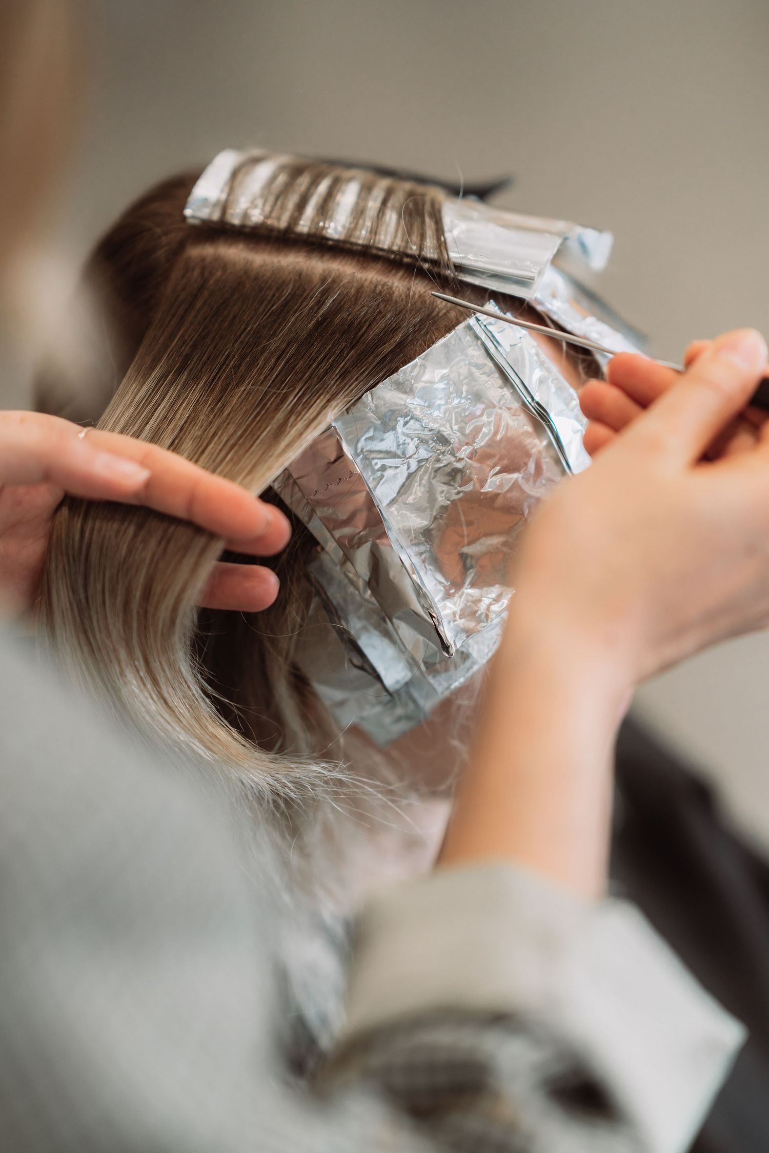 Close-up of foil highlights being applied to hair sections.