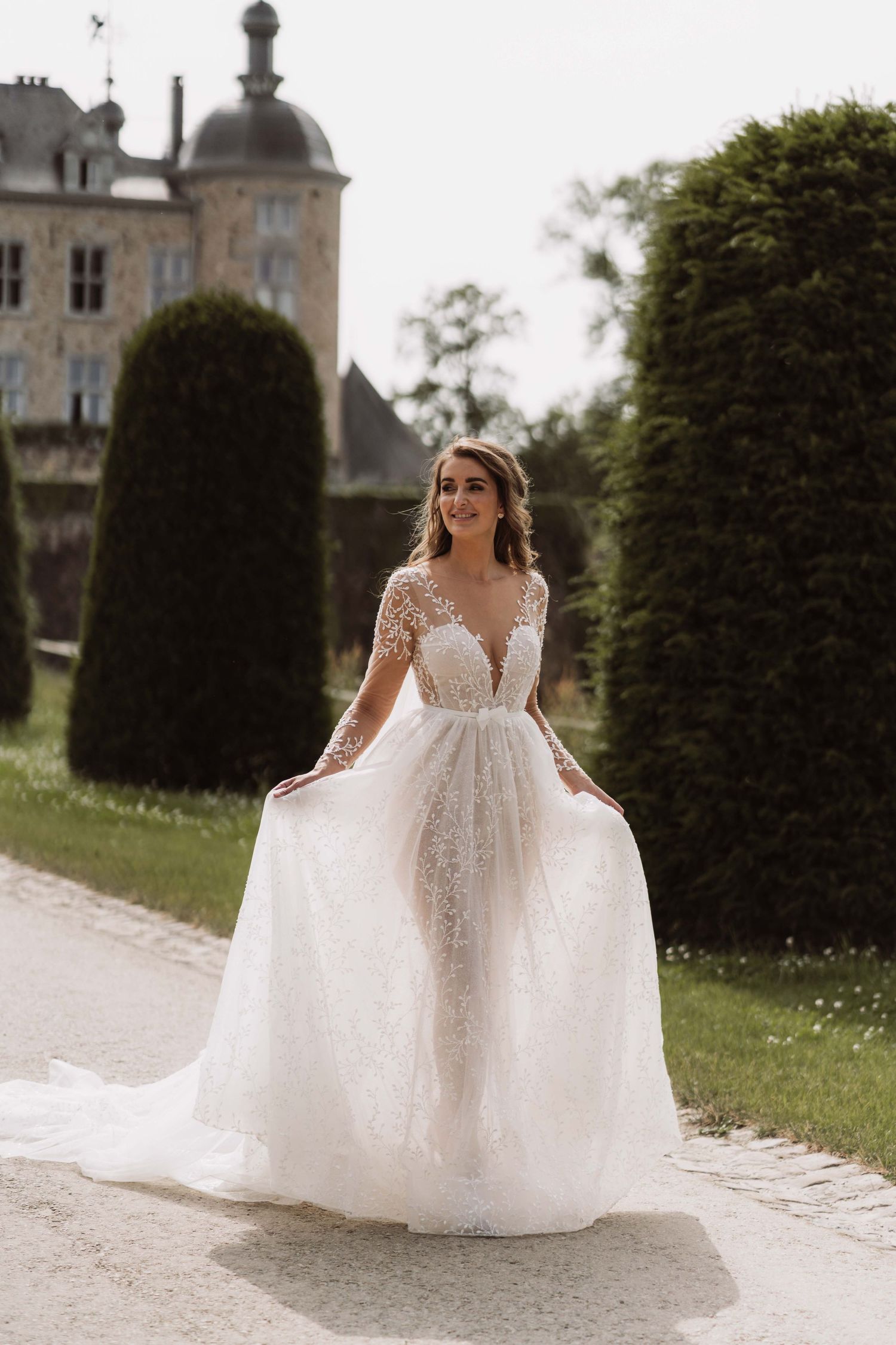 Elegant wedding dress with flowing tulle skirt and lace details photographed in sequence against castle grounds.