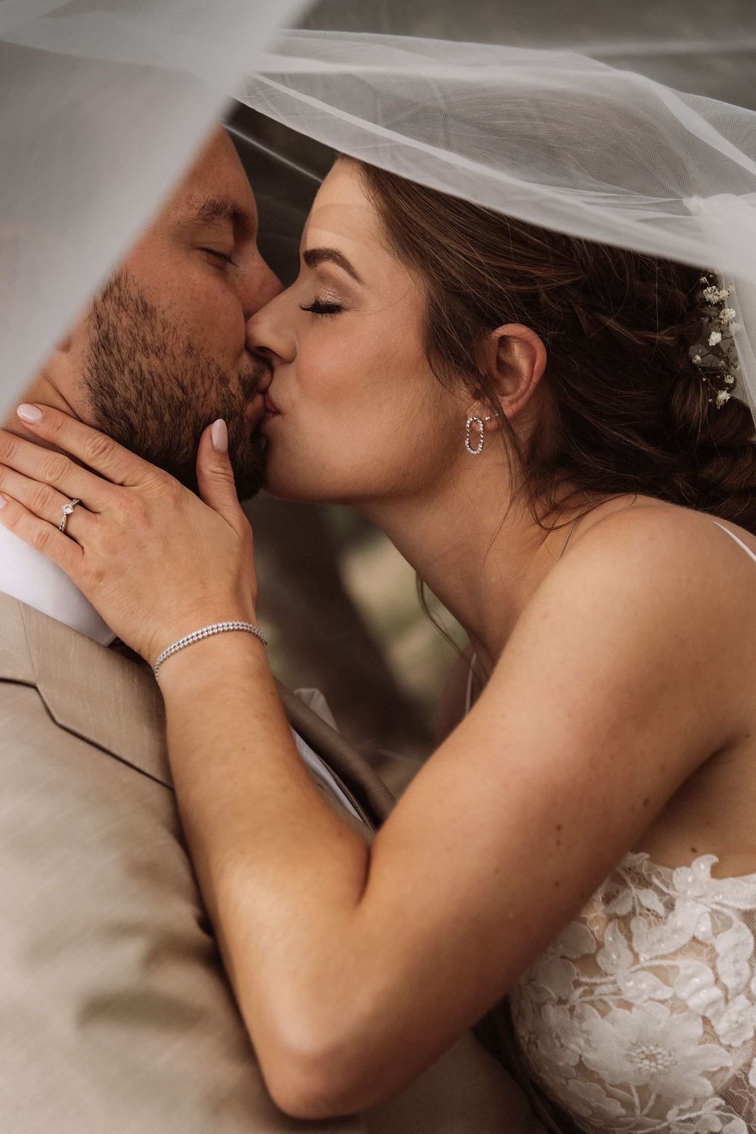 Intimate wedding portrait captured in soft natural lighting with flowing veil.