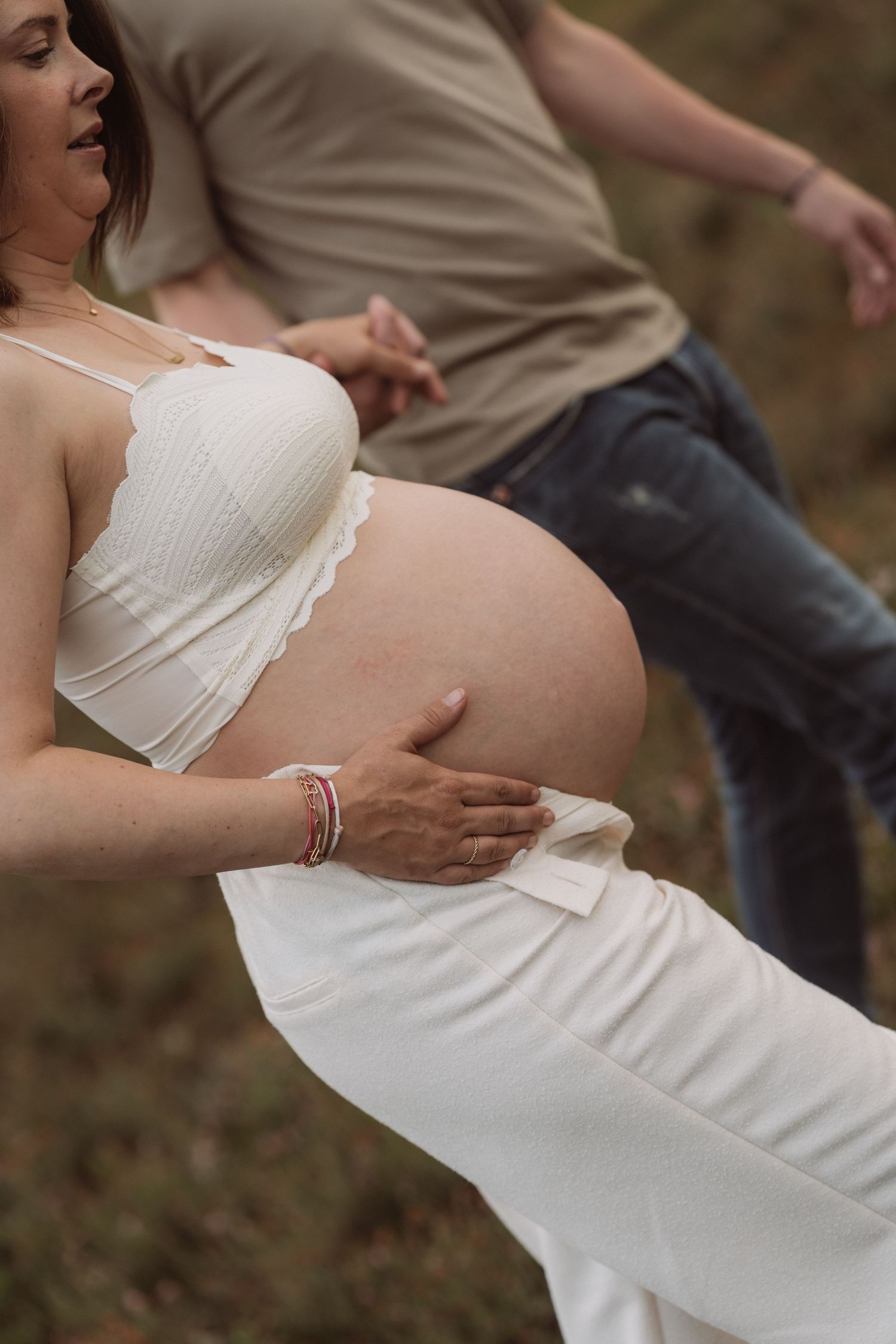 Intimate maternity photo showing hands cradling a pregnant belly in natural light.