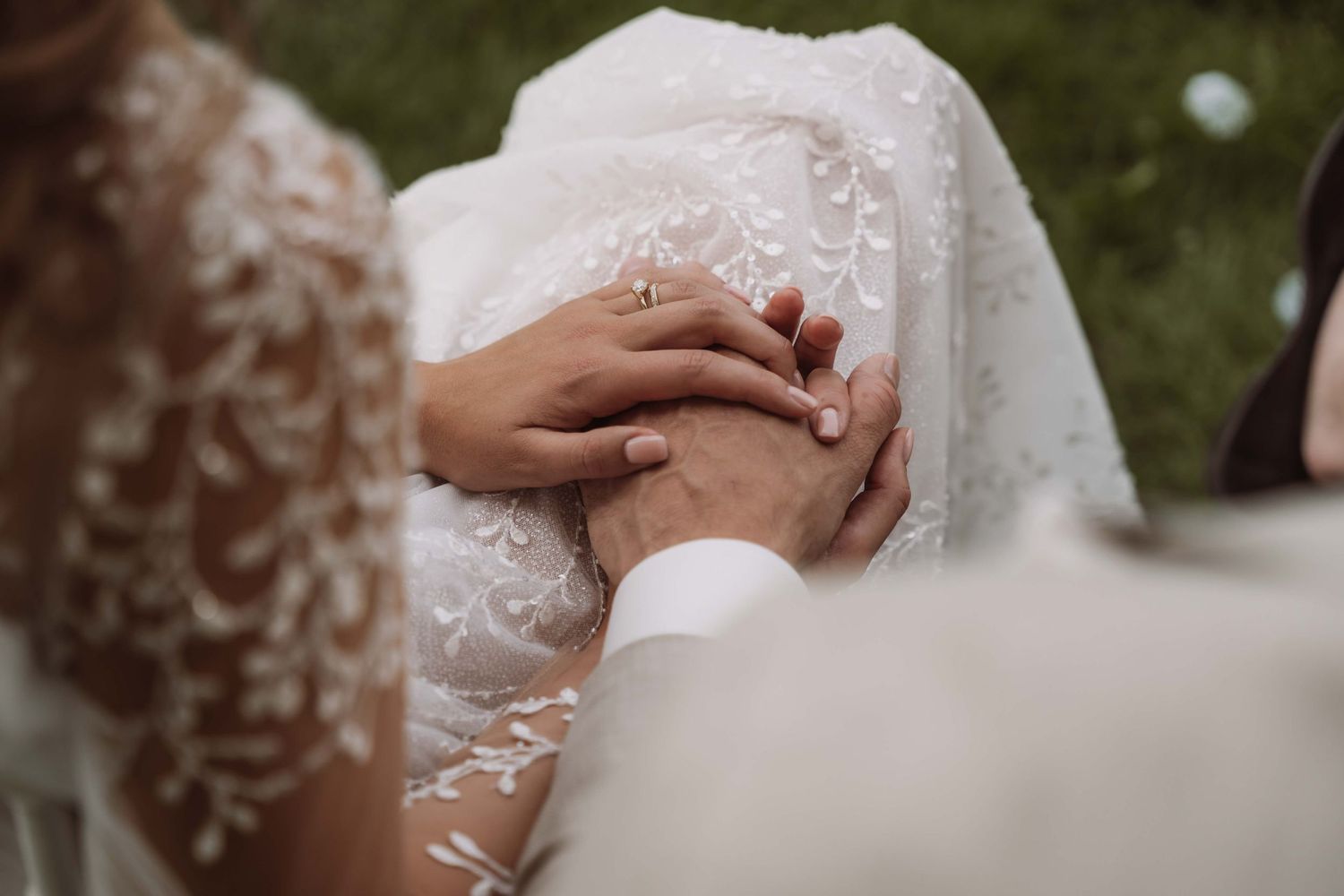 Close-up details of wedding rings being exchanged during an elegant outdoor ceremony.