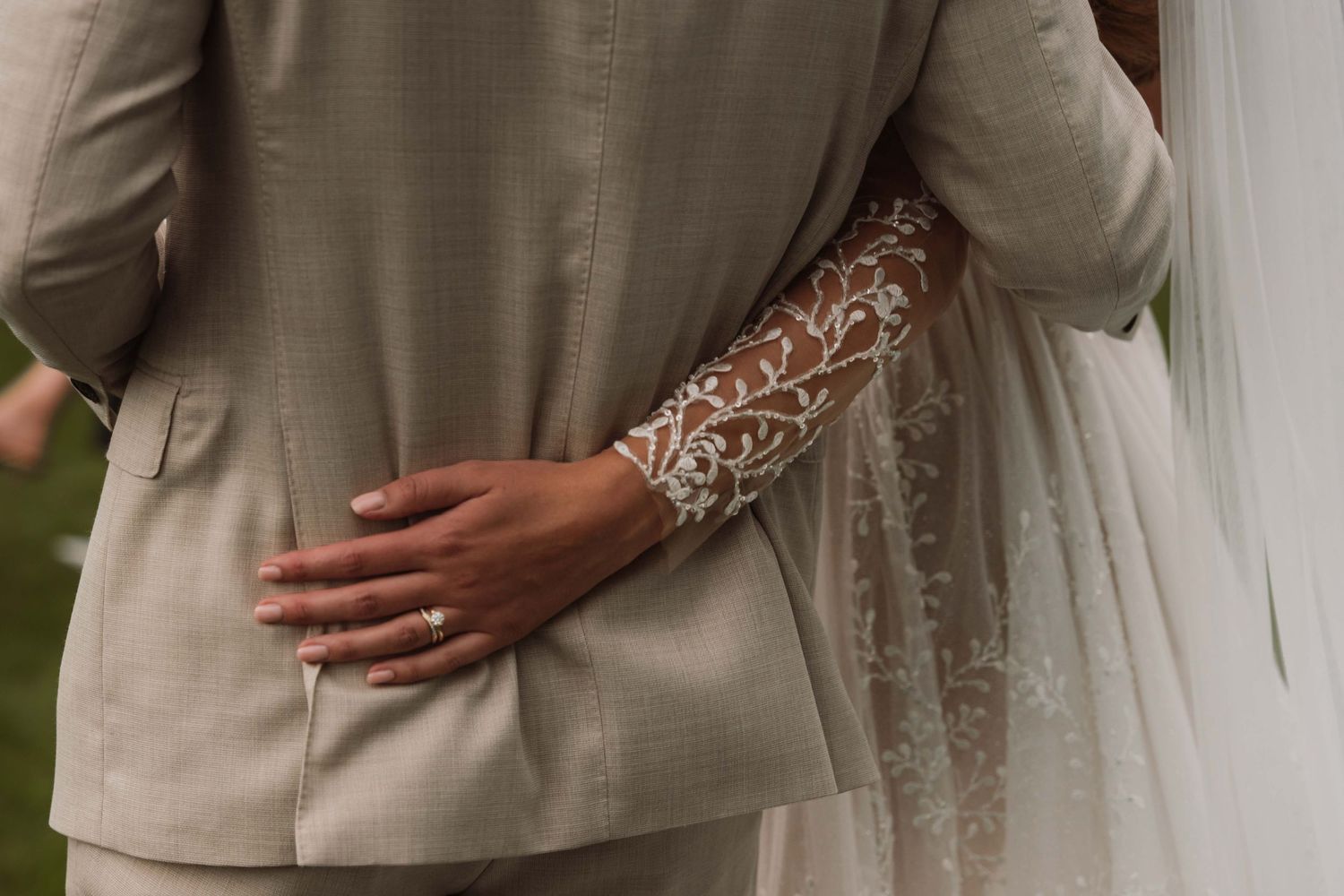A bride and groom embrace during their wedding ceremony in elegant beige and white attire.