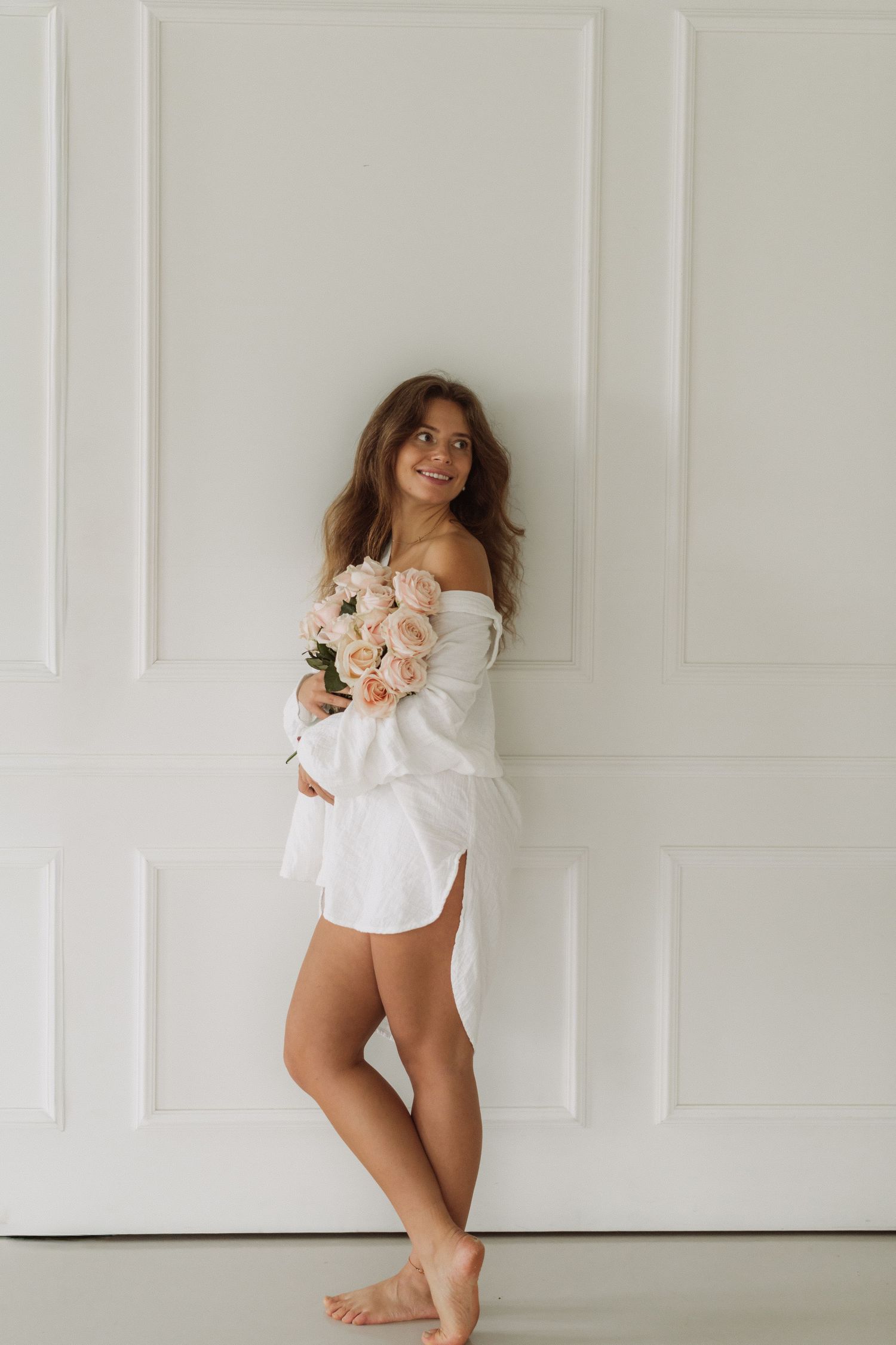 Woman in white shirt poses playfully against white paneled wall in a series of candid shots.