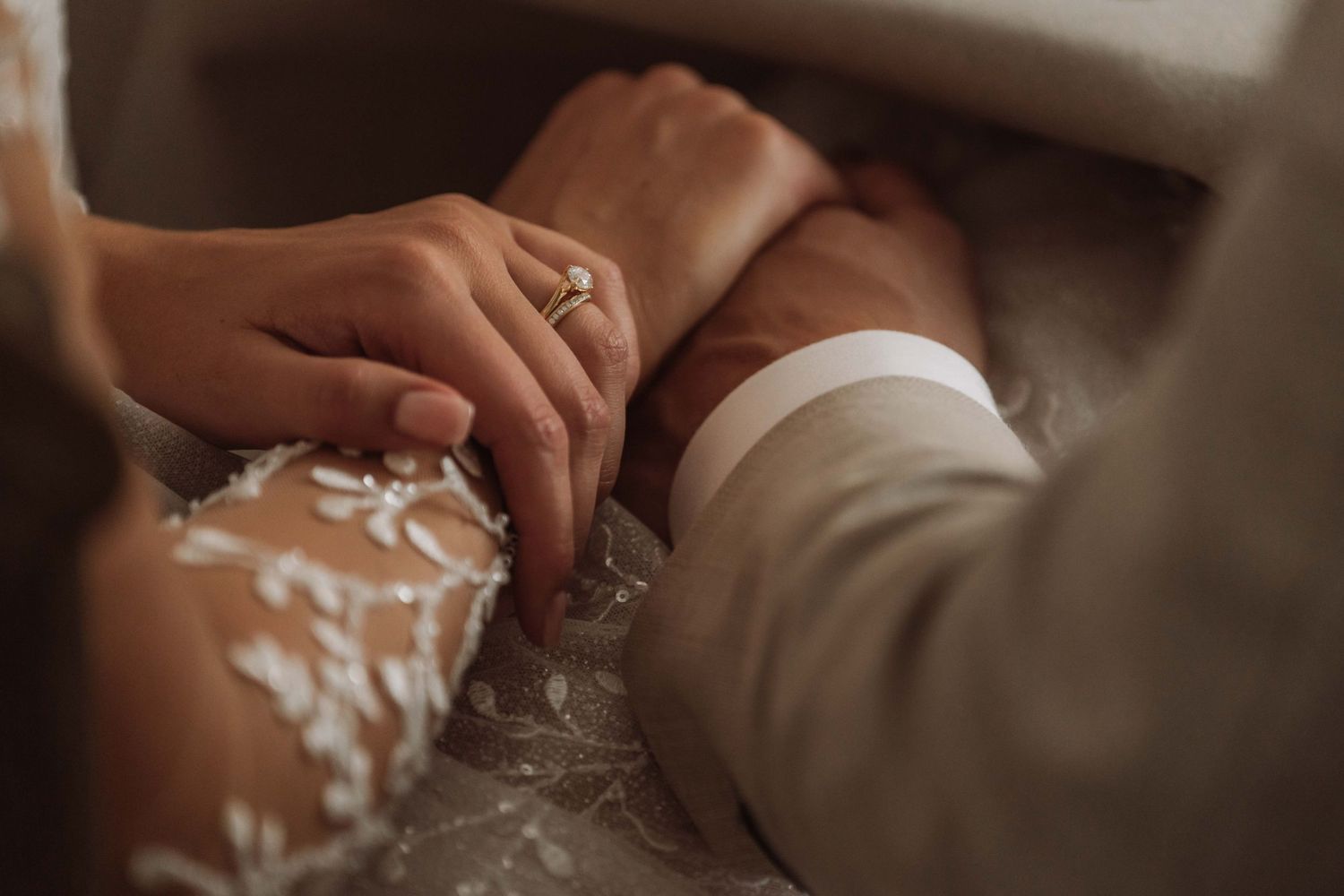 Close-up of hands holding a white coffee mug with a decorative design in a cozy indoor setting.
