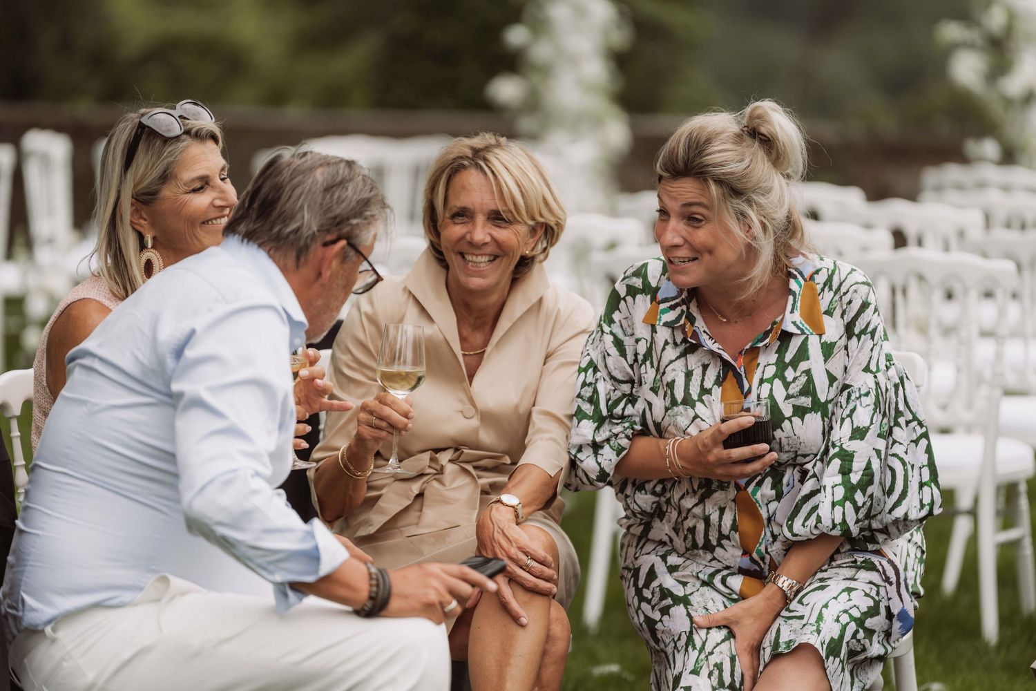 A series of candid moments captured at an outdoor wedding reception with guests sharing joyful embraces and laughter.