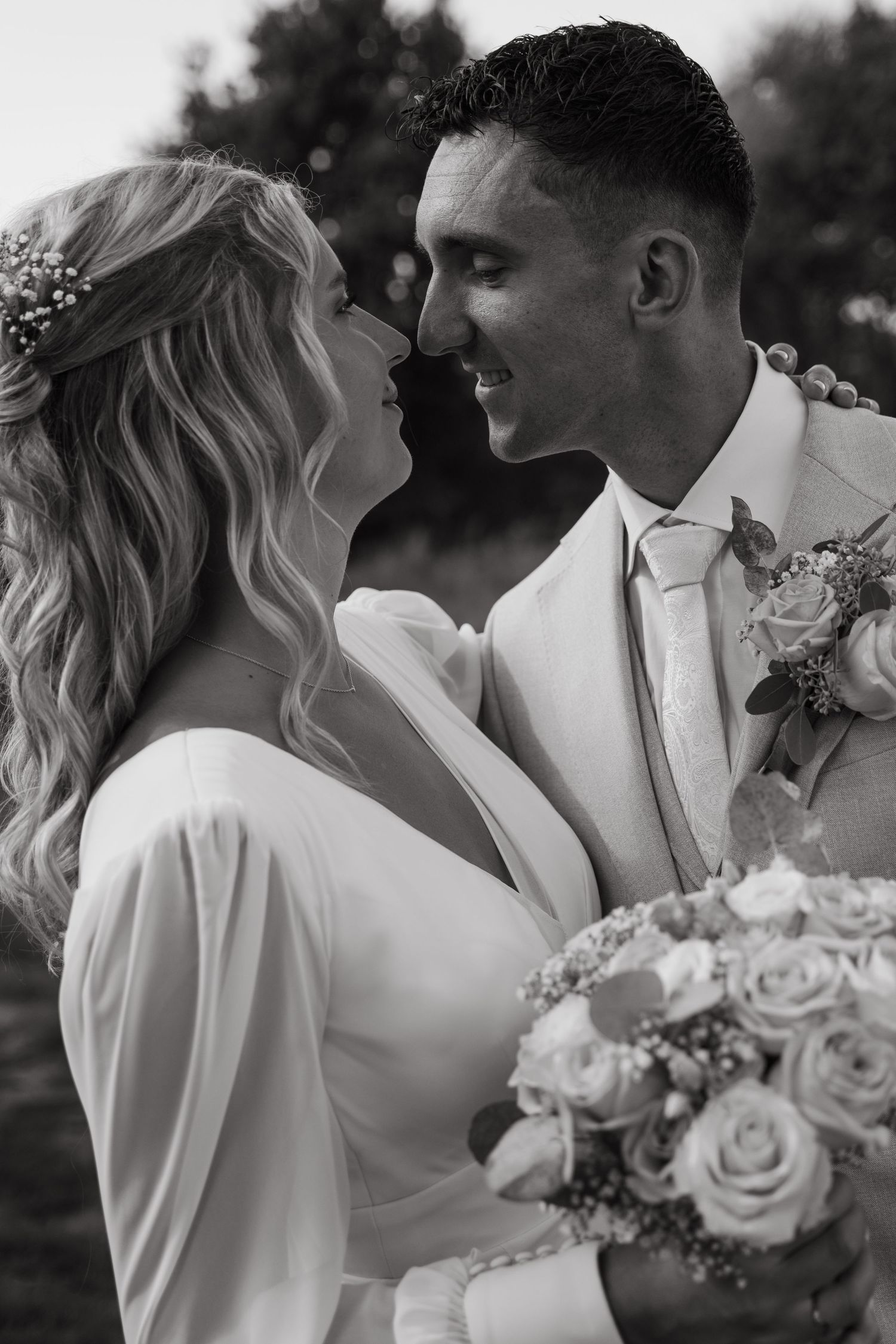 Romantic black and white wedding portrait with couple embracing and holding a rose bouquet.