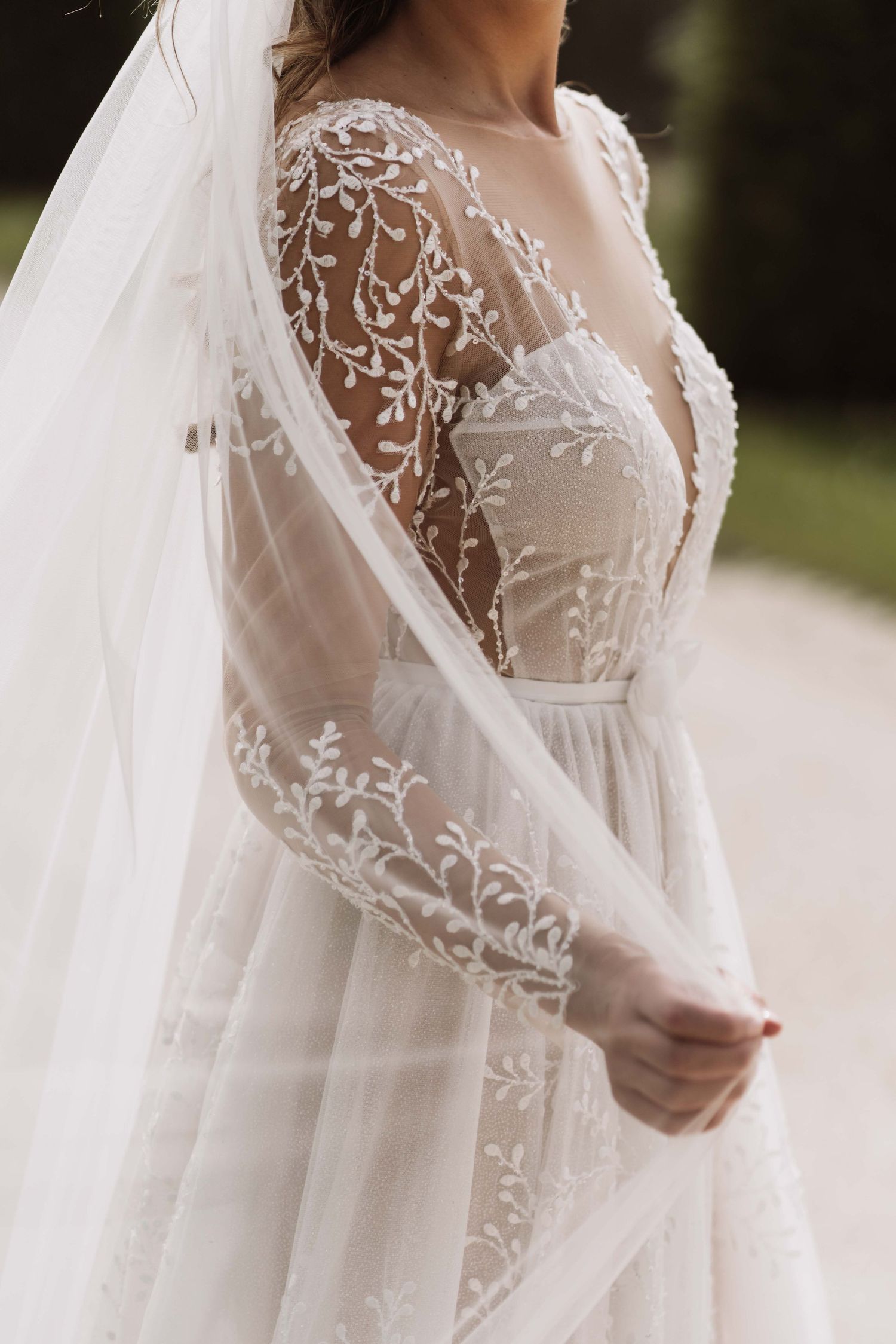 Close-up detail of delicate white lace embroidery and sheer fabric on a romantic wedding gown sleeve.