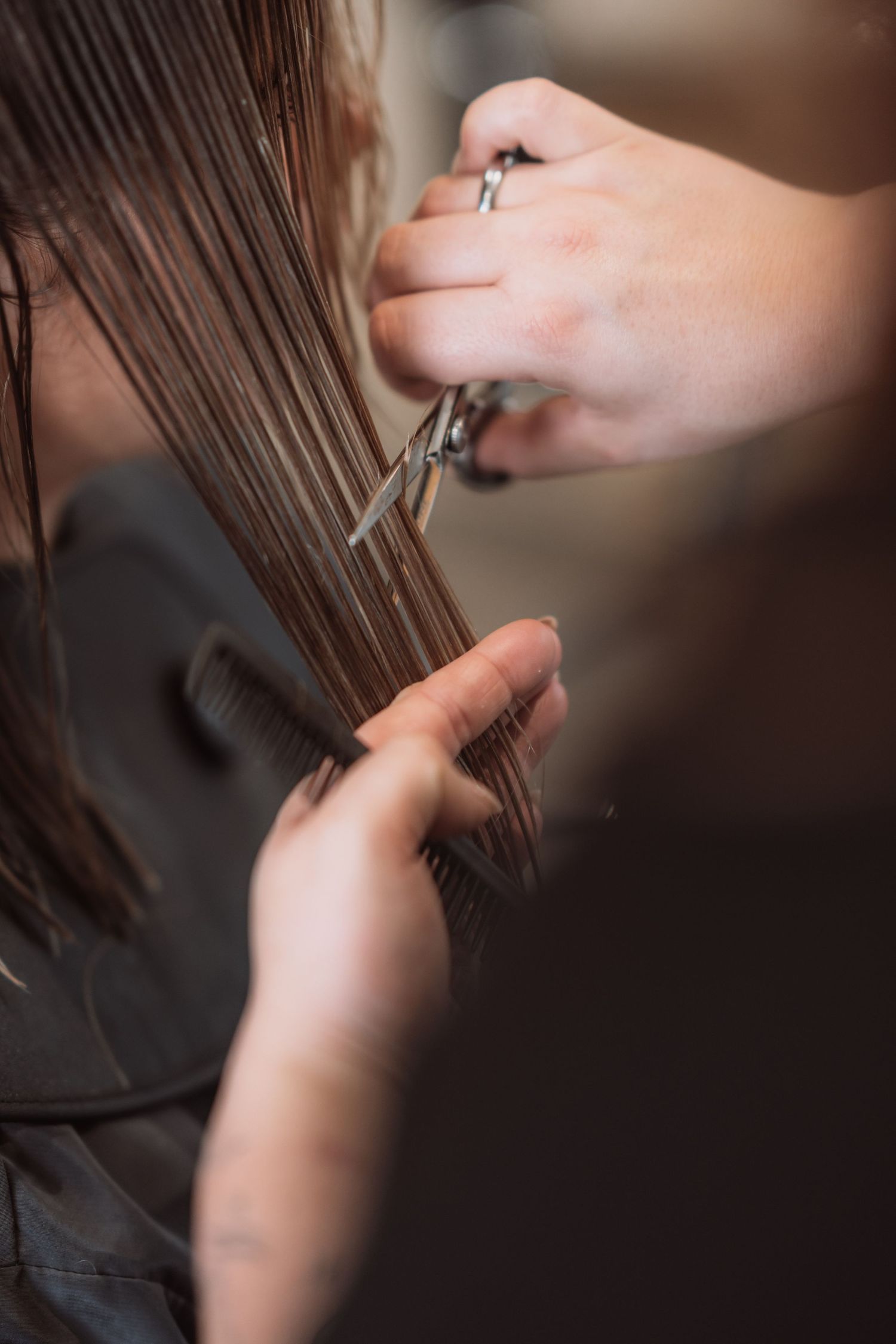 Close-up of hands cutting hair with professional scissors in a salon setting.