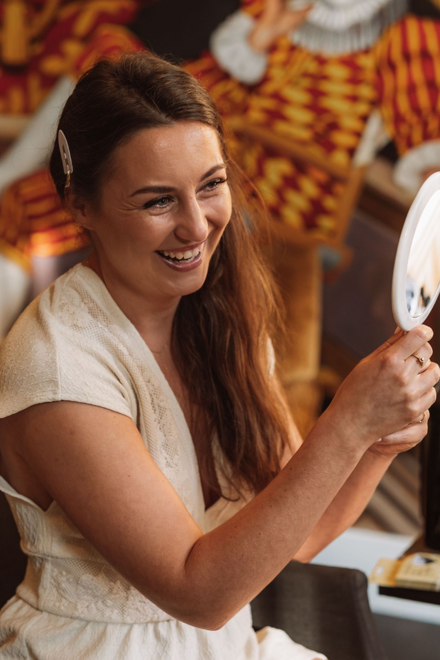 Woman in white dress laughs while holding coffee cup in warm lighting.