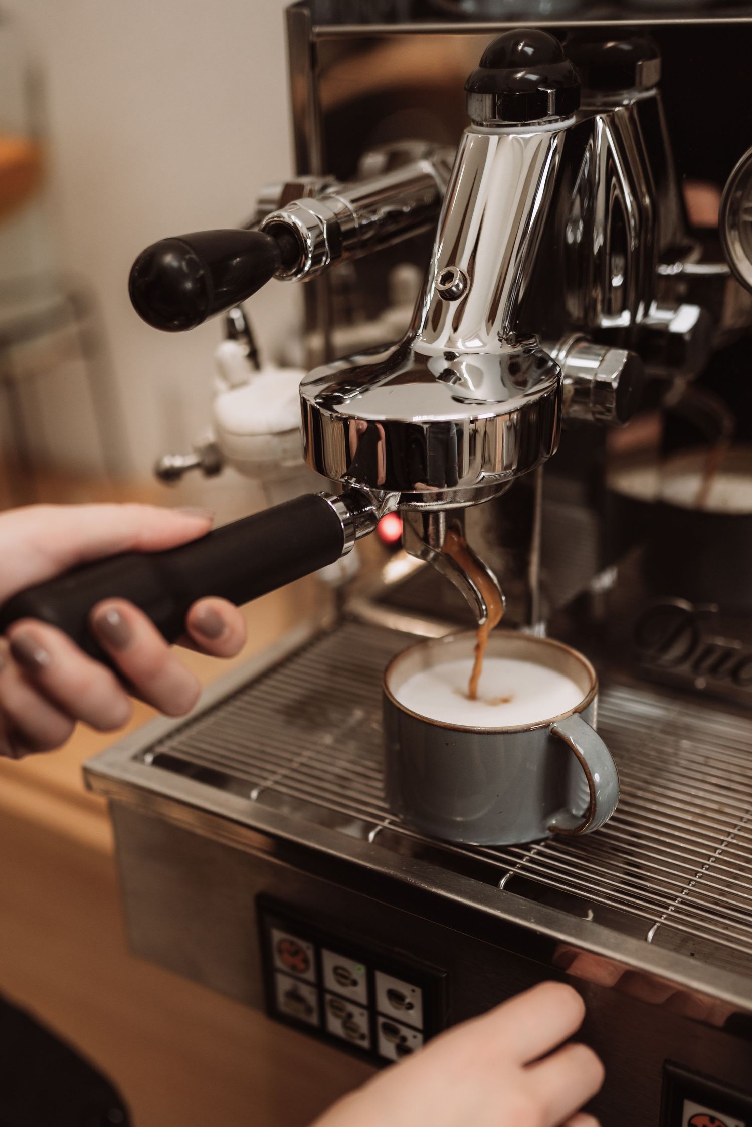 Professional espresso machine brewing coffee with steam rising from the portafilter.