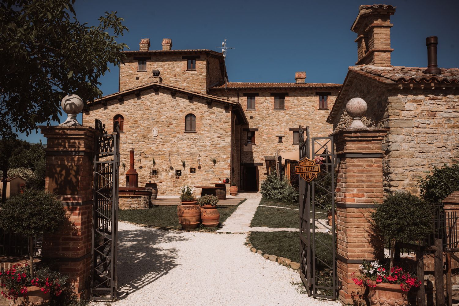Traditional stone buildings and cobblestone paths in a sunny Tuscan hillside village.