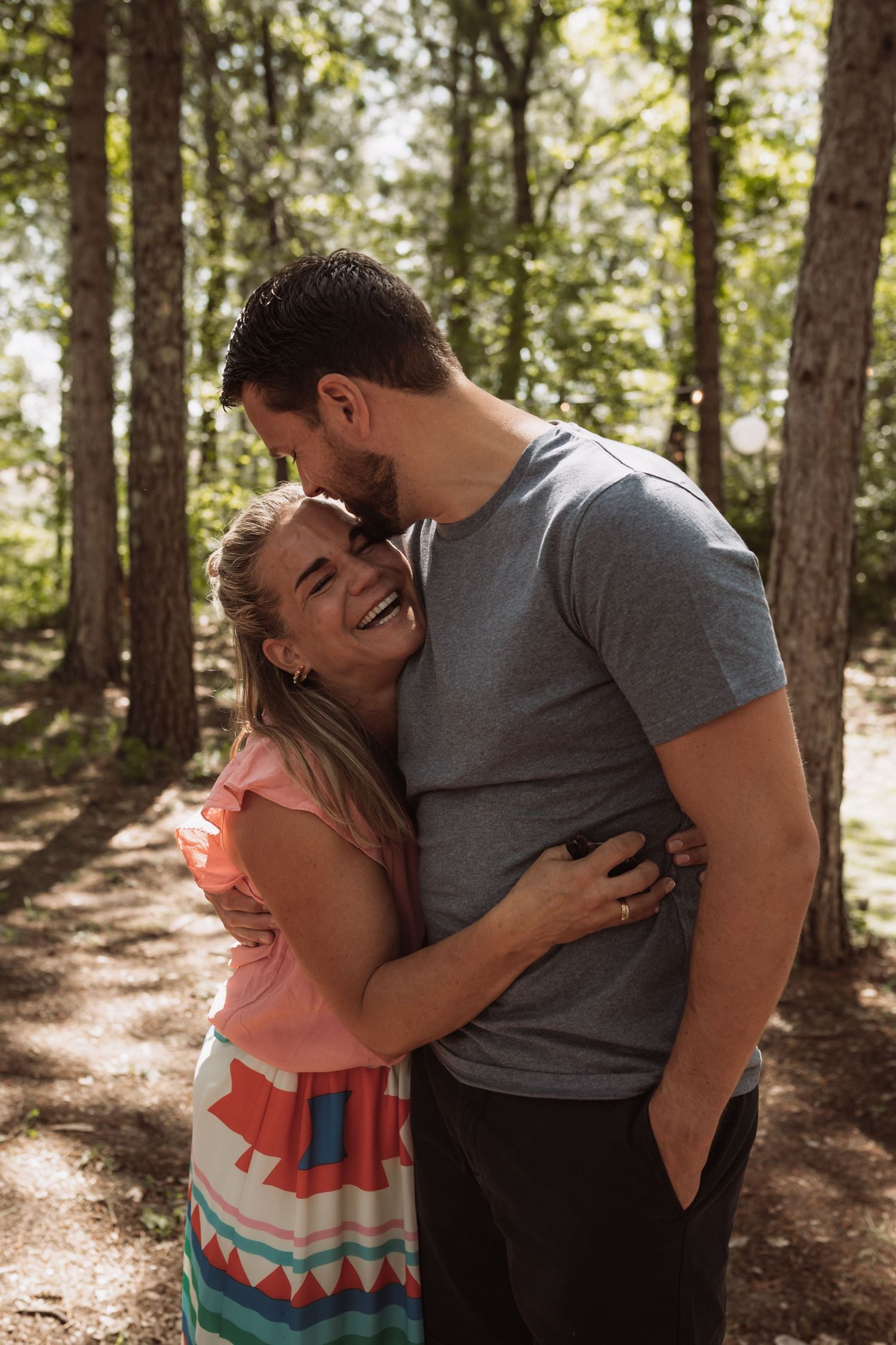 A couple shares intimate moments in a sunlit forest setting, shown in a series of candid photos.