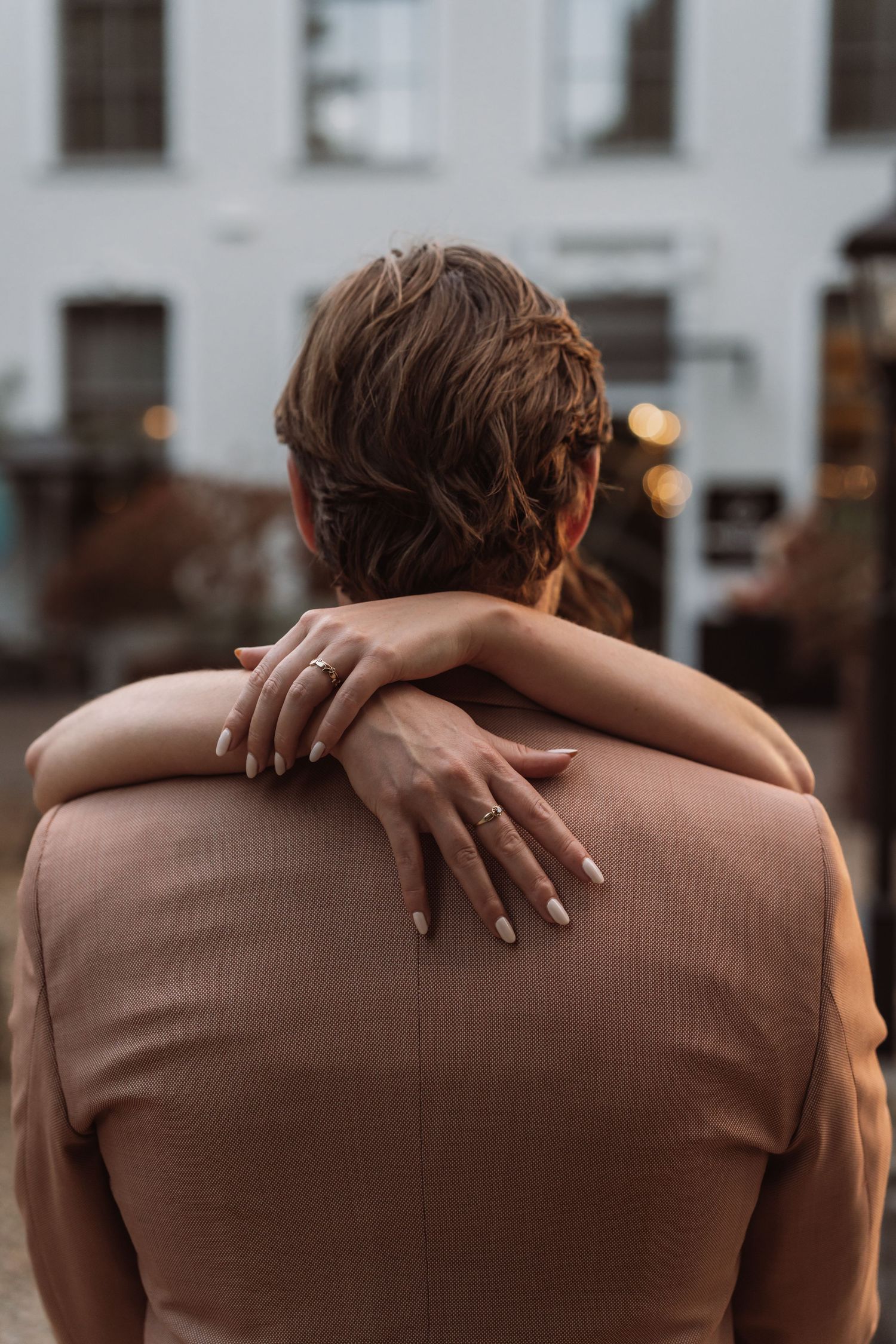 A person embraces another from behind, shown in a series of intimate cropped photos wearing a brown sweater.