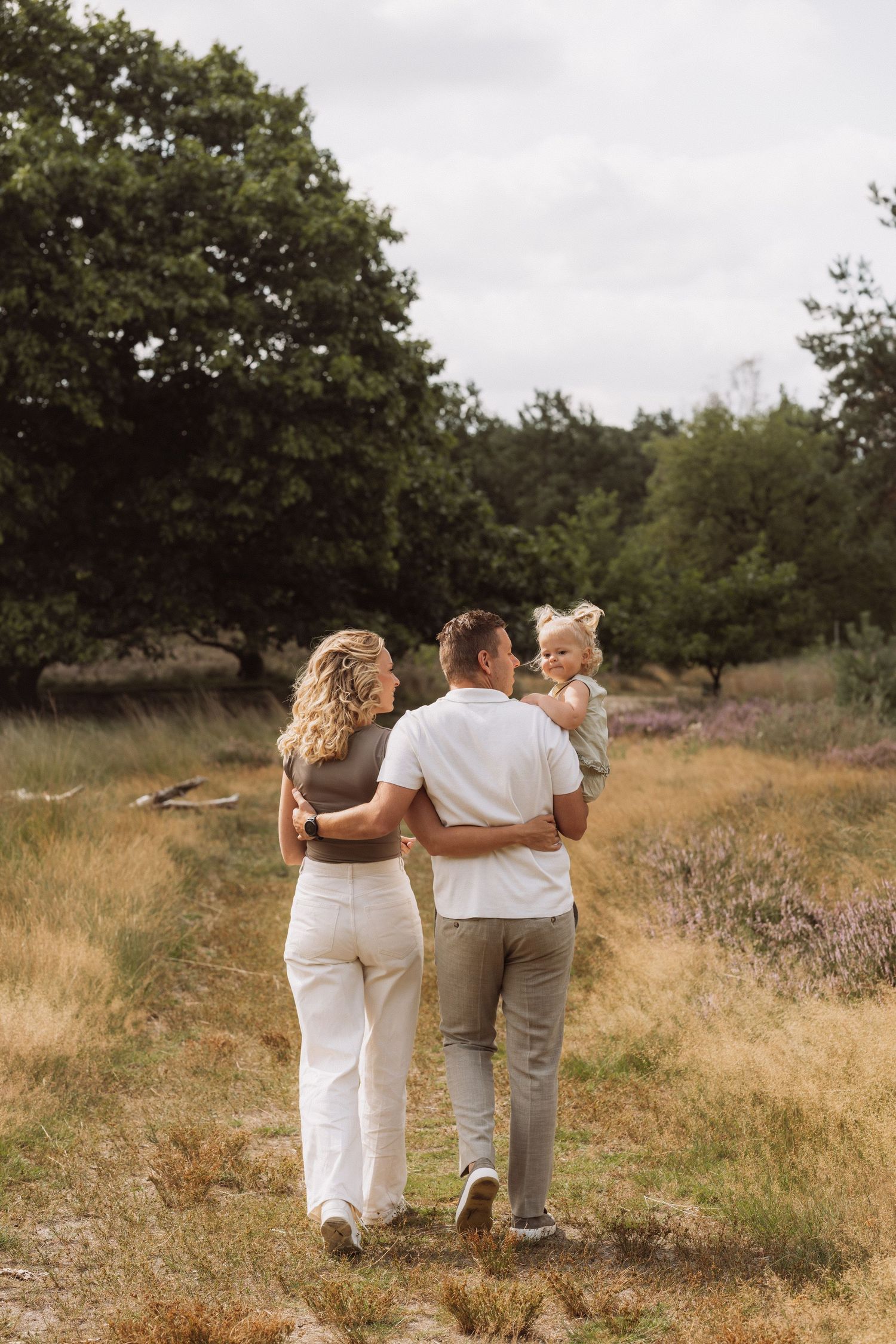 Family walking together on a nature trail during sunset.