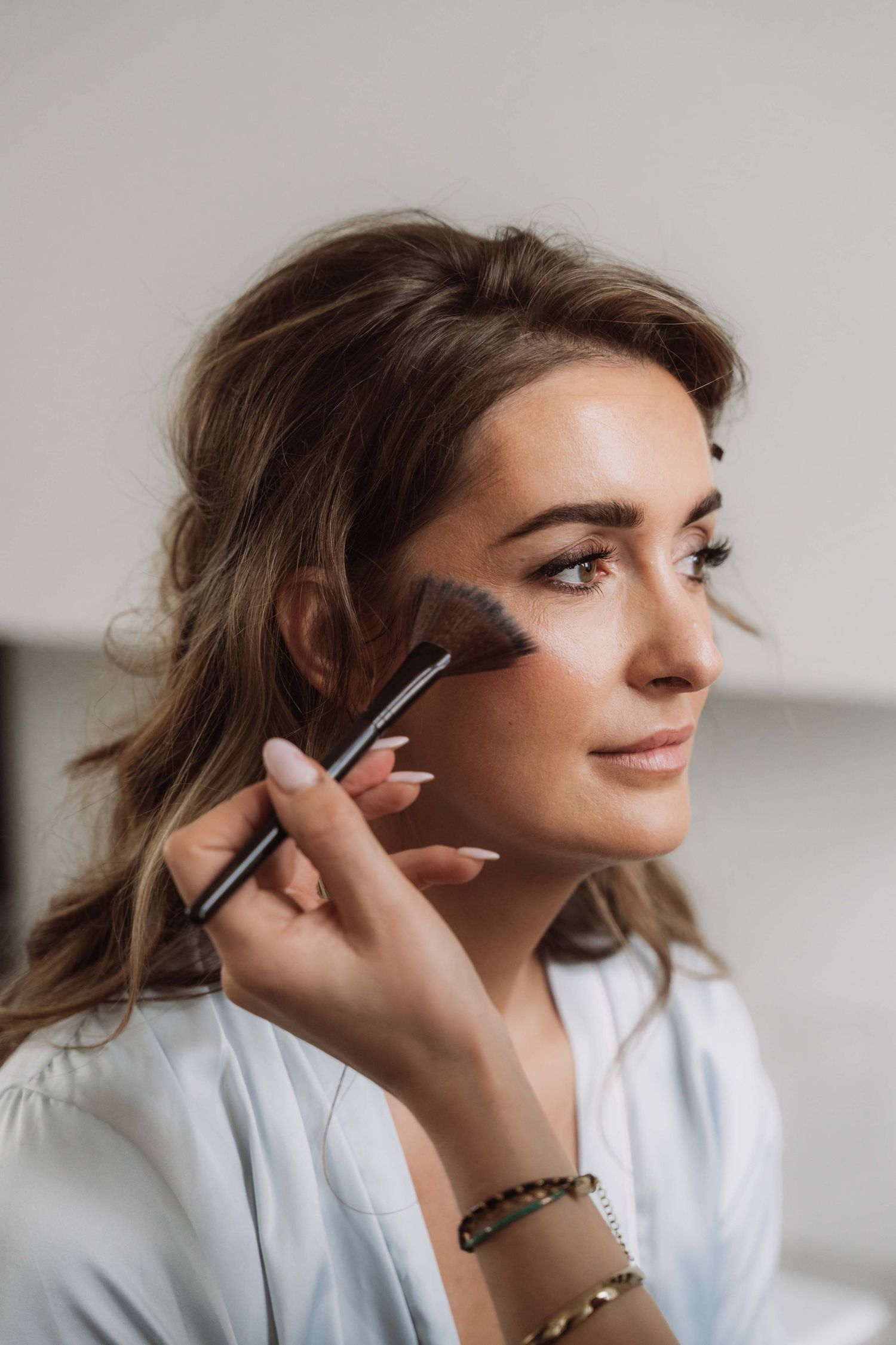 A series of shots showing makeup application using a brush on someone wearing a white shirt.