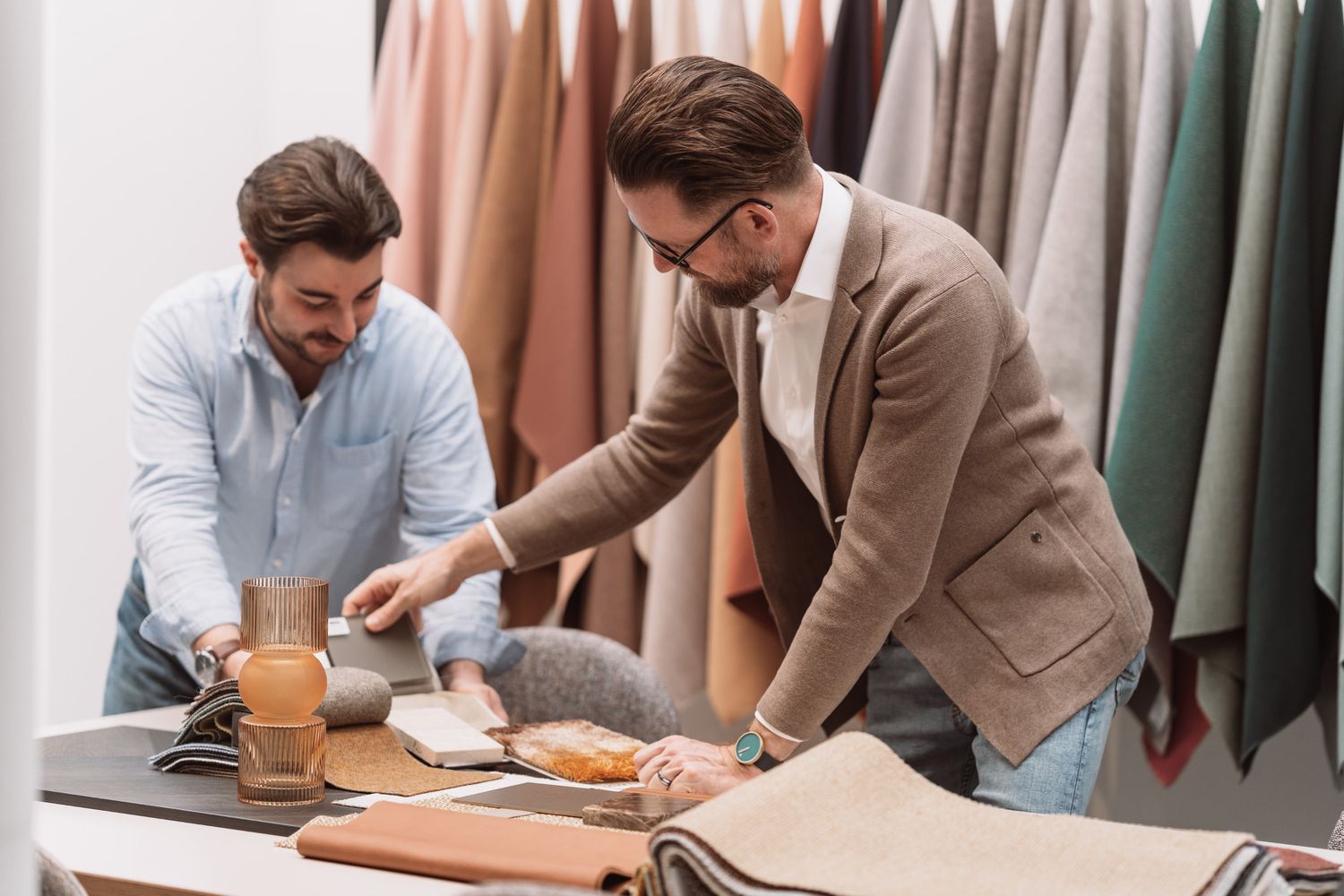 Two business professionals reviewing documents and discussing work together at a modern office desk.