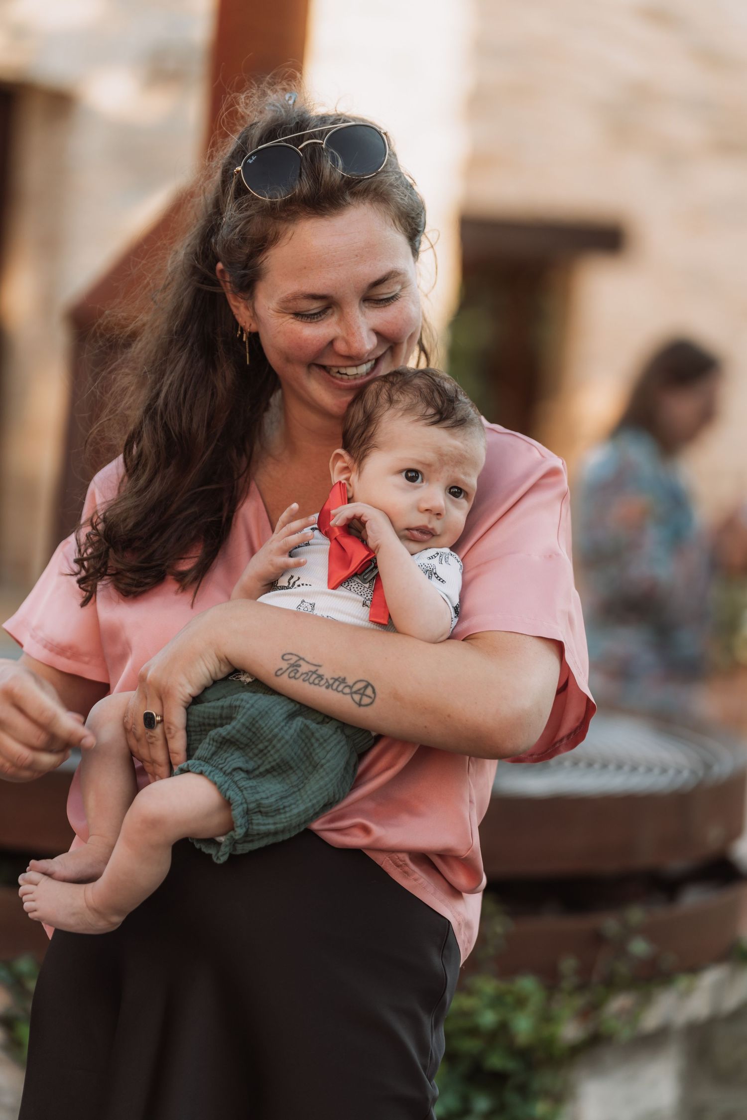 A mother in a pink top playfully embraces and tickles her laughing toddler in a series of candid outdoor moments.