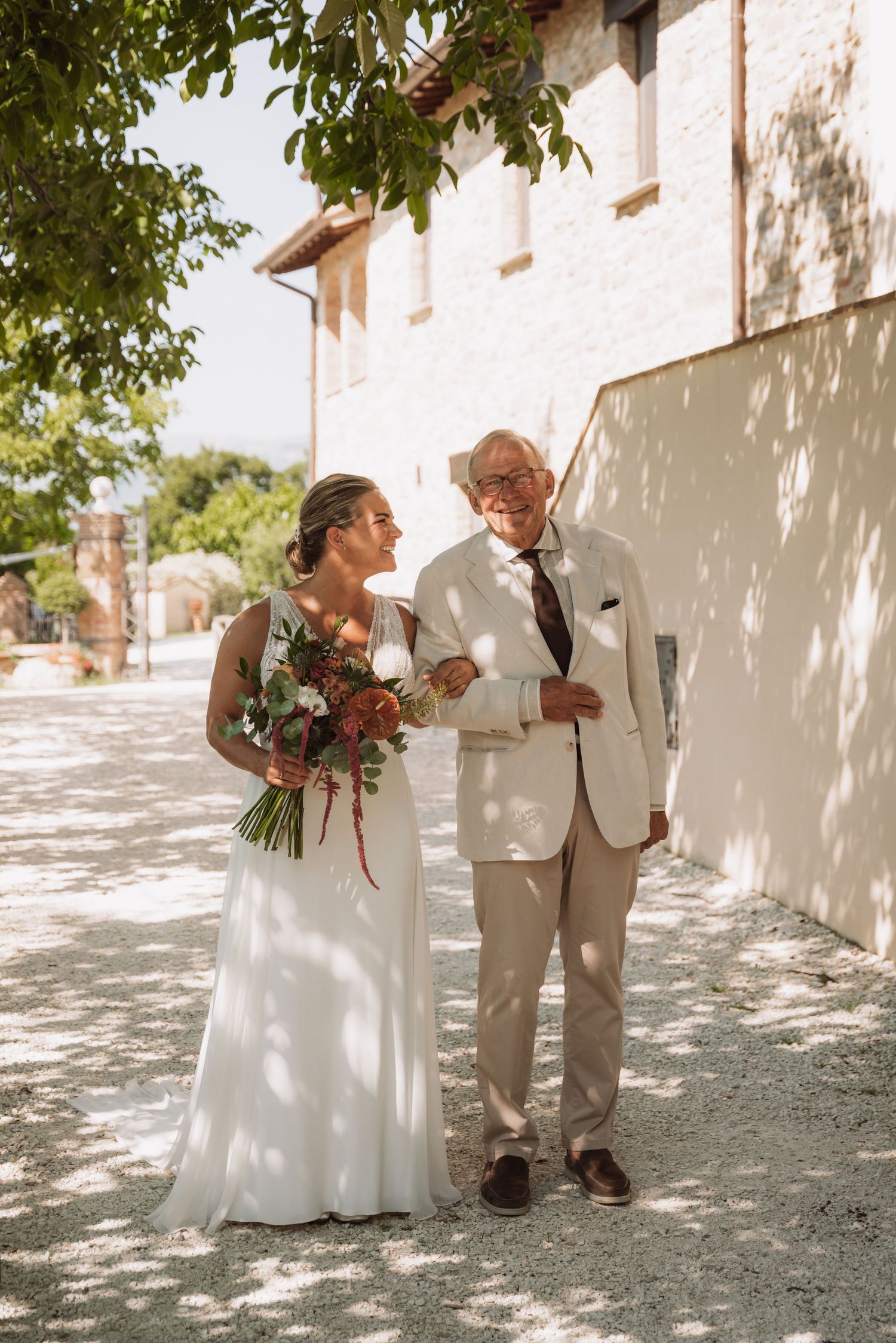 A couple shares sweet moments in a series of romantic first look wedding photos against a sunlit white wall.