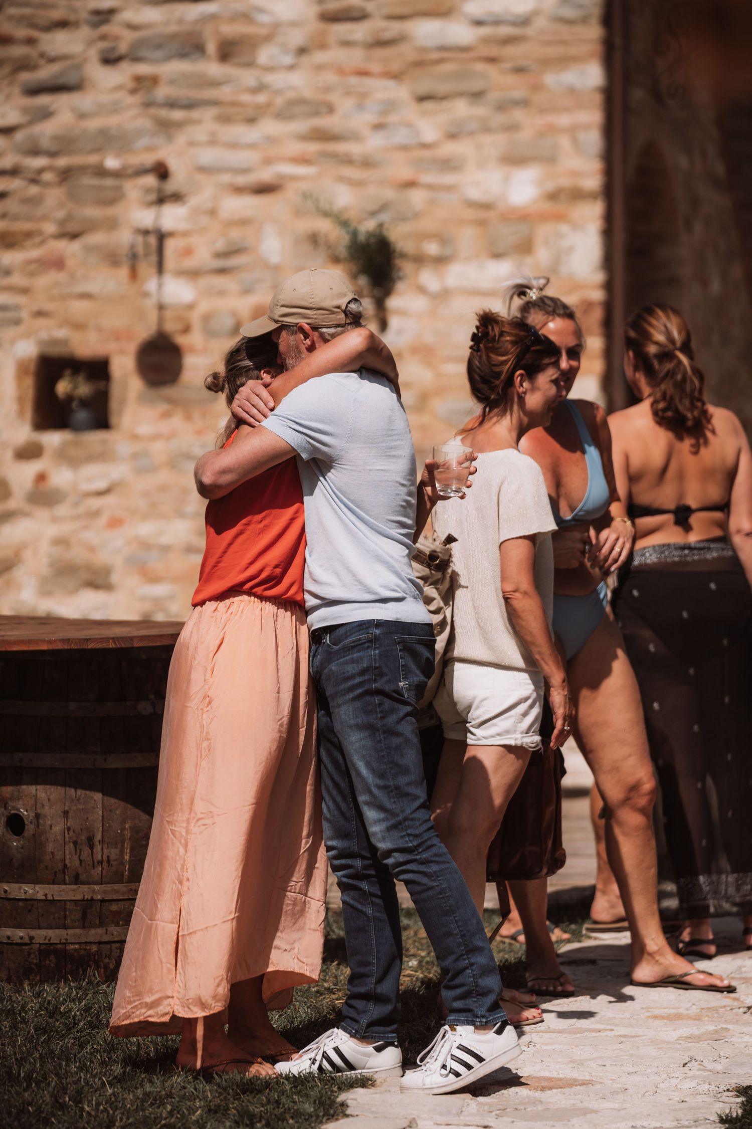 Group of people bent over examining something on a stone wall with rustic texture in background.