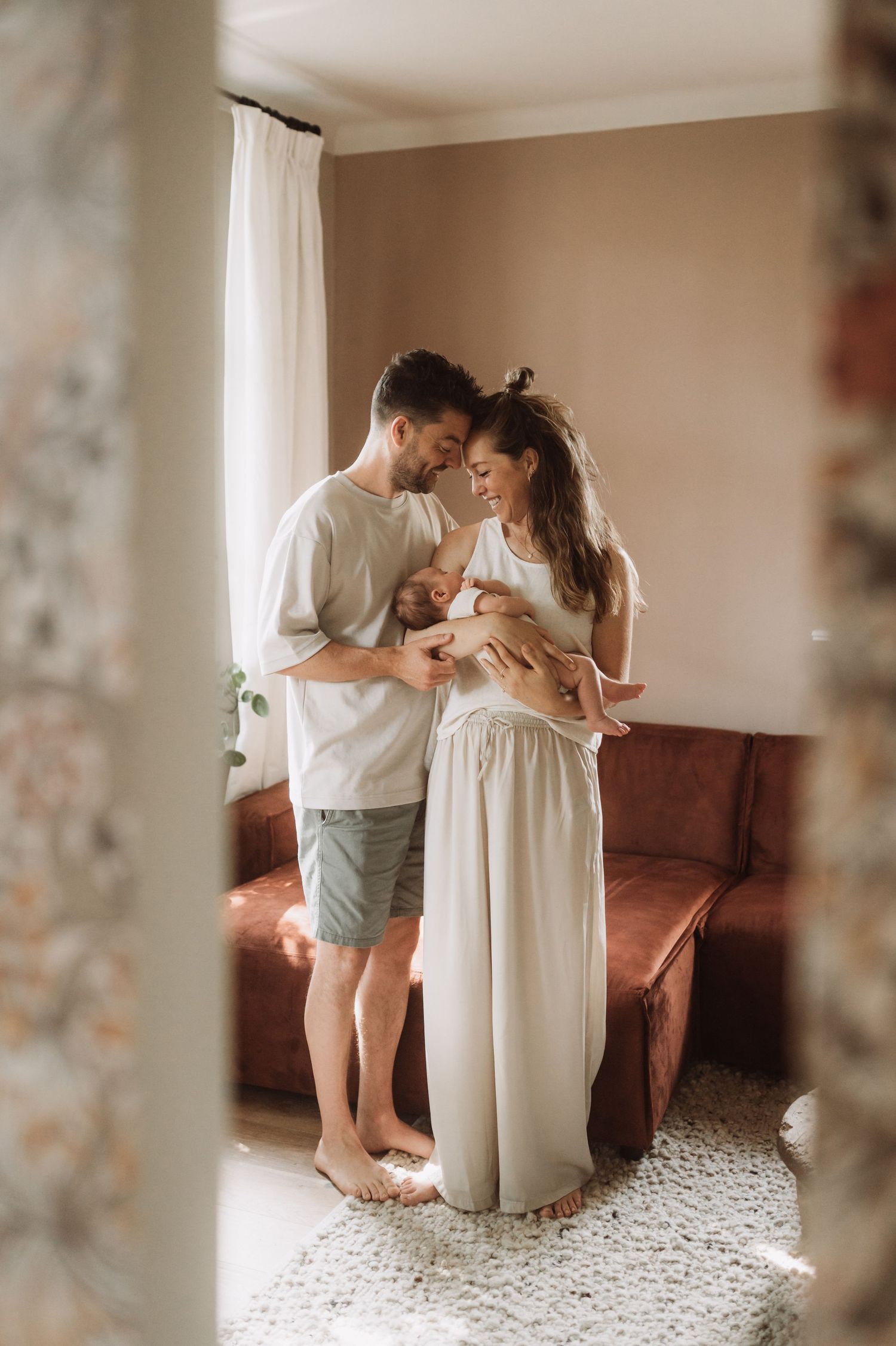 Family sharing intimate moments together on a patterned rug in a bright indoor setting.
