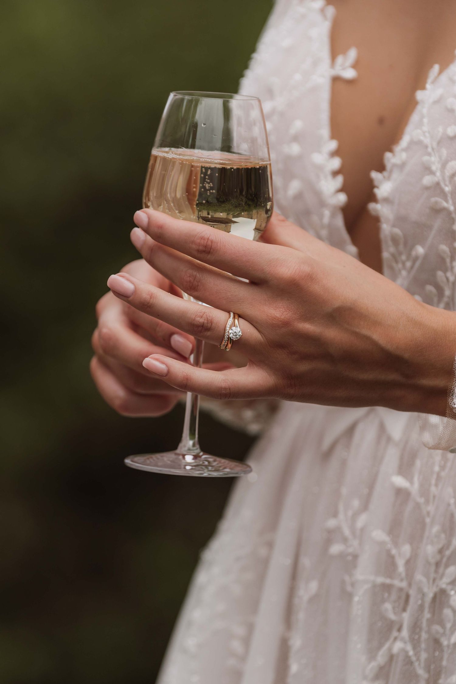 Close-up shots of hands holding champagne glasses while wearing a delicate white lace wedding dress.