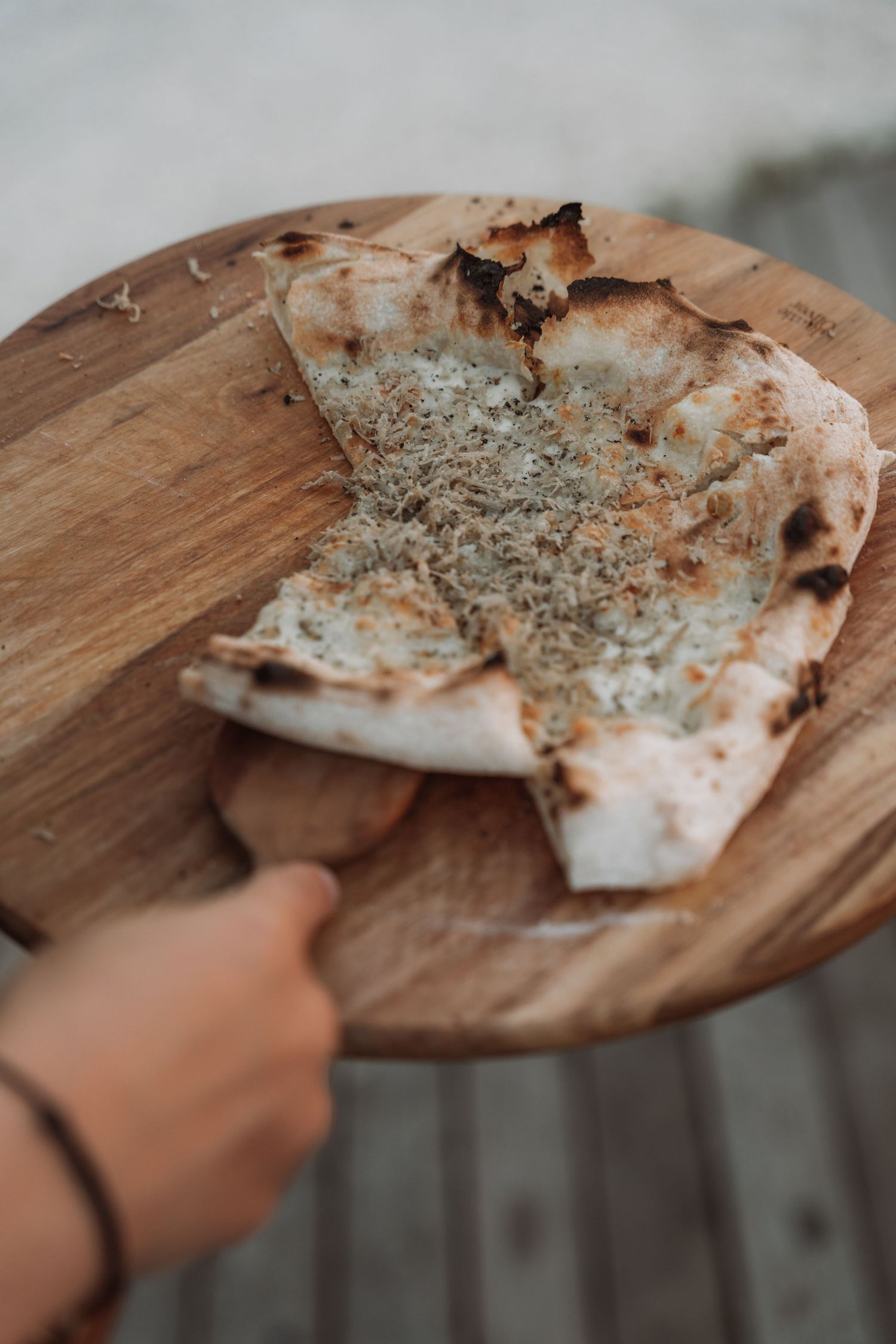 A wooden cutting board holds pieces of flatbread topped with herbs and seasonings shown in a series of photos.