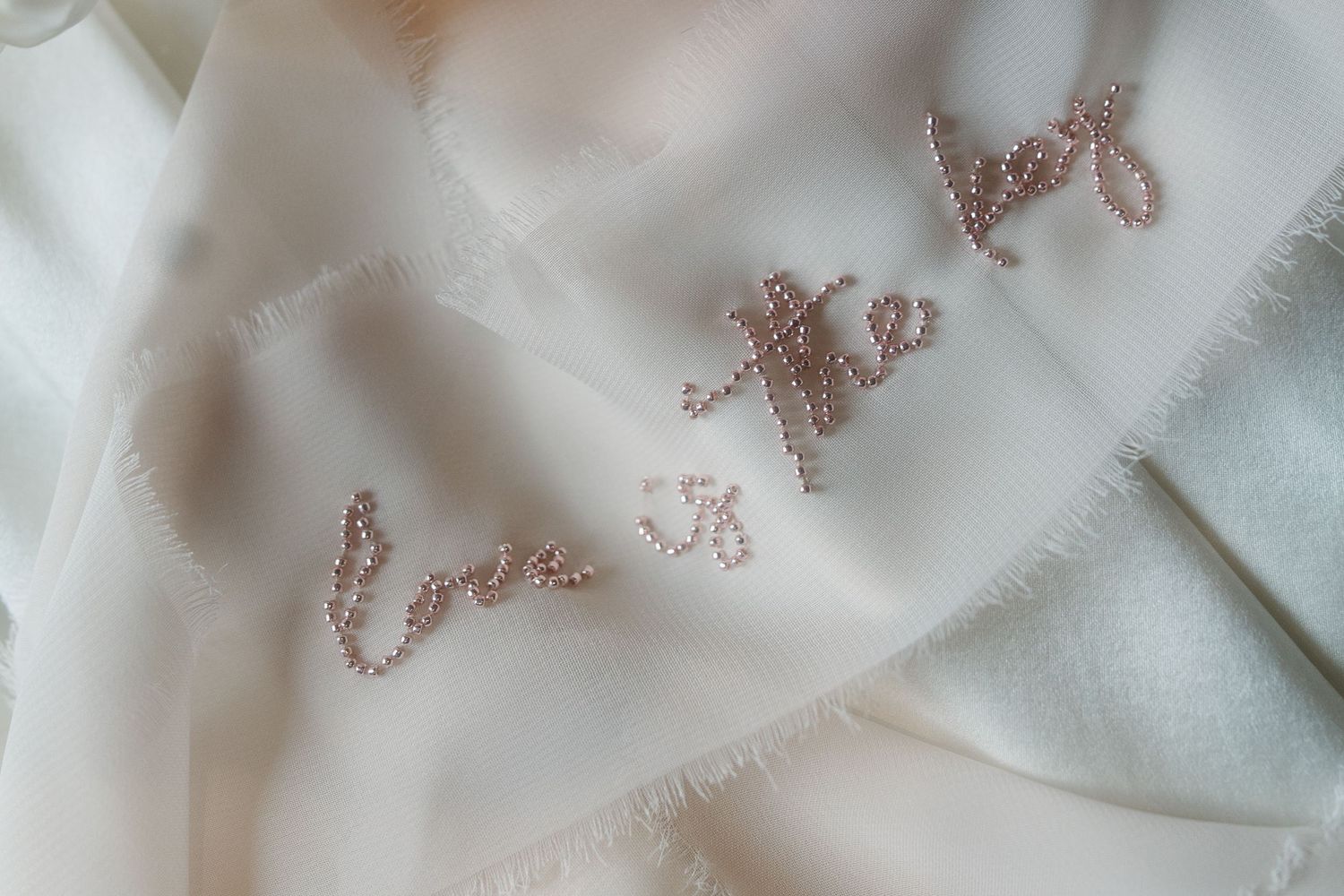 Delicate glitter text detail embroidered on white silk fabric.