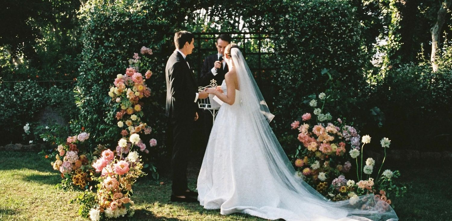 Romantic garden wedding setting with floral arch and natural greenery backdrop.