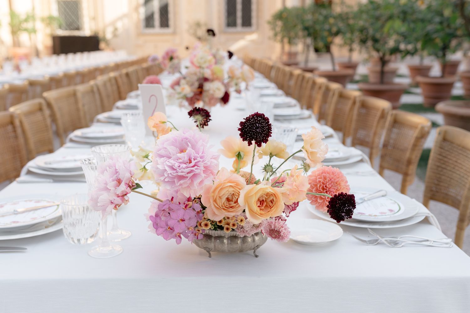 Long elegant wedding reception tables set with pink floral centerpieces and gold chairs.