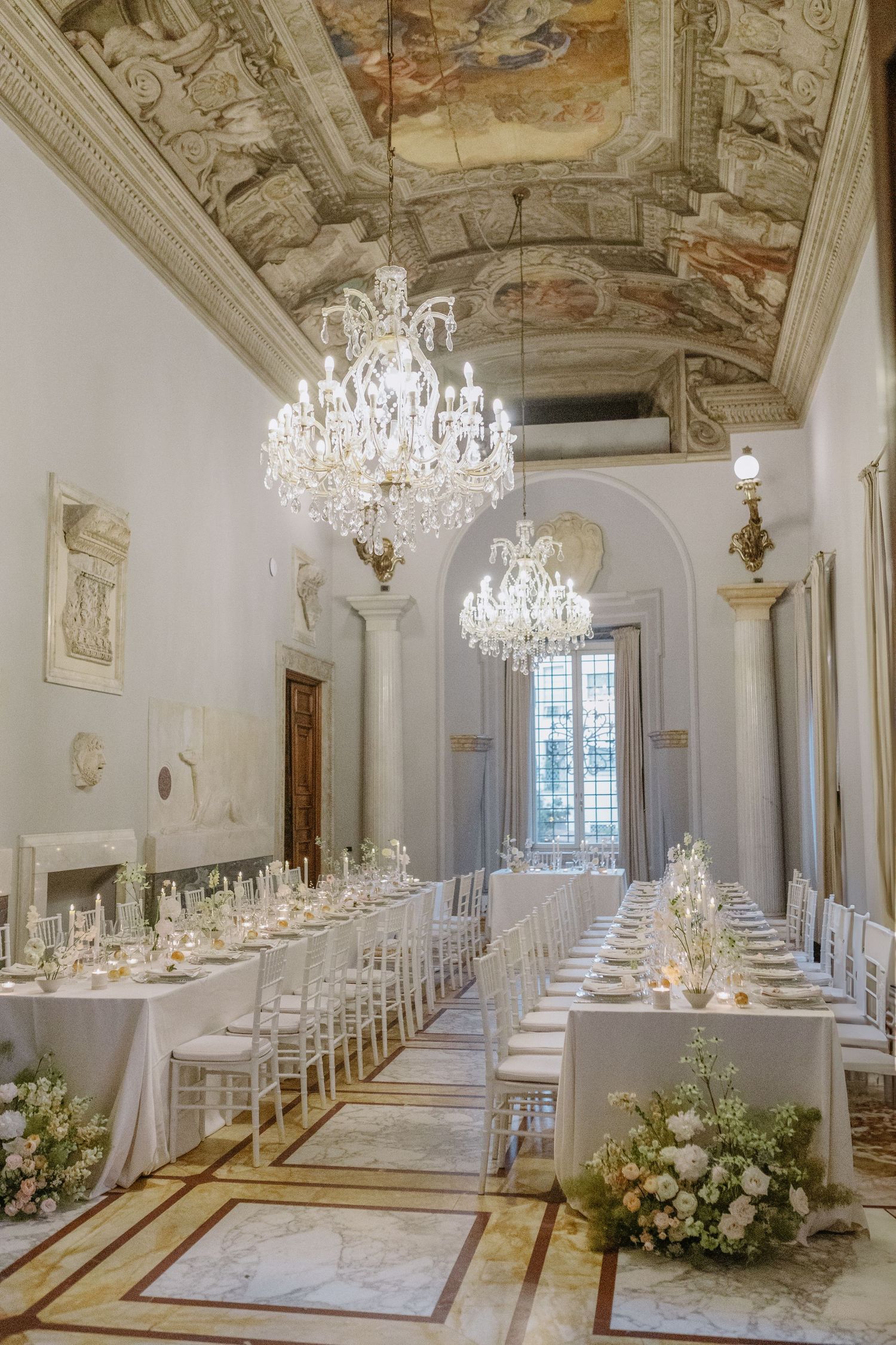 Elegant white reception hall with crystal chandeliers and ornate ceiling frescoes, for a stunning destination wedding in Italy