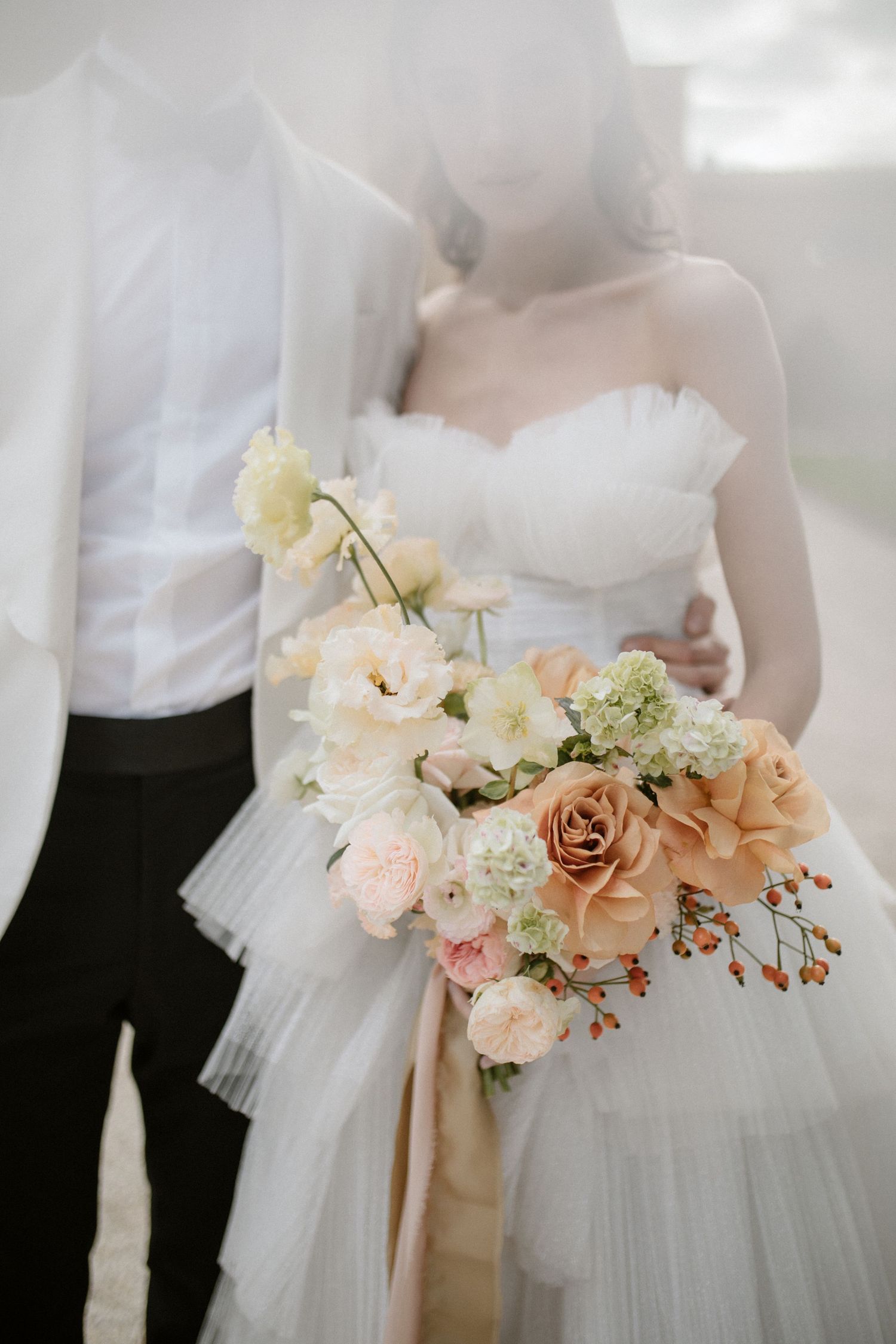 Delicate peach and blush floral sash adorns a white tulle gown.