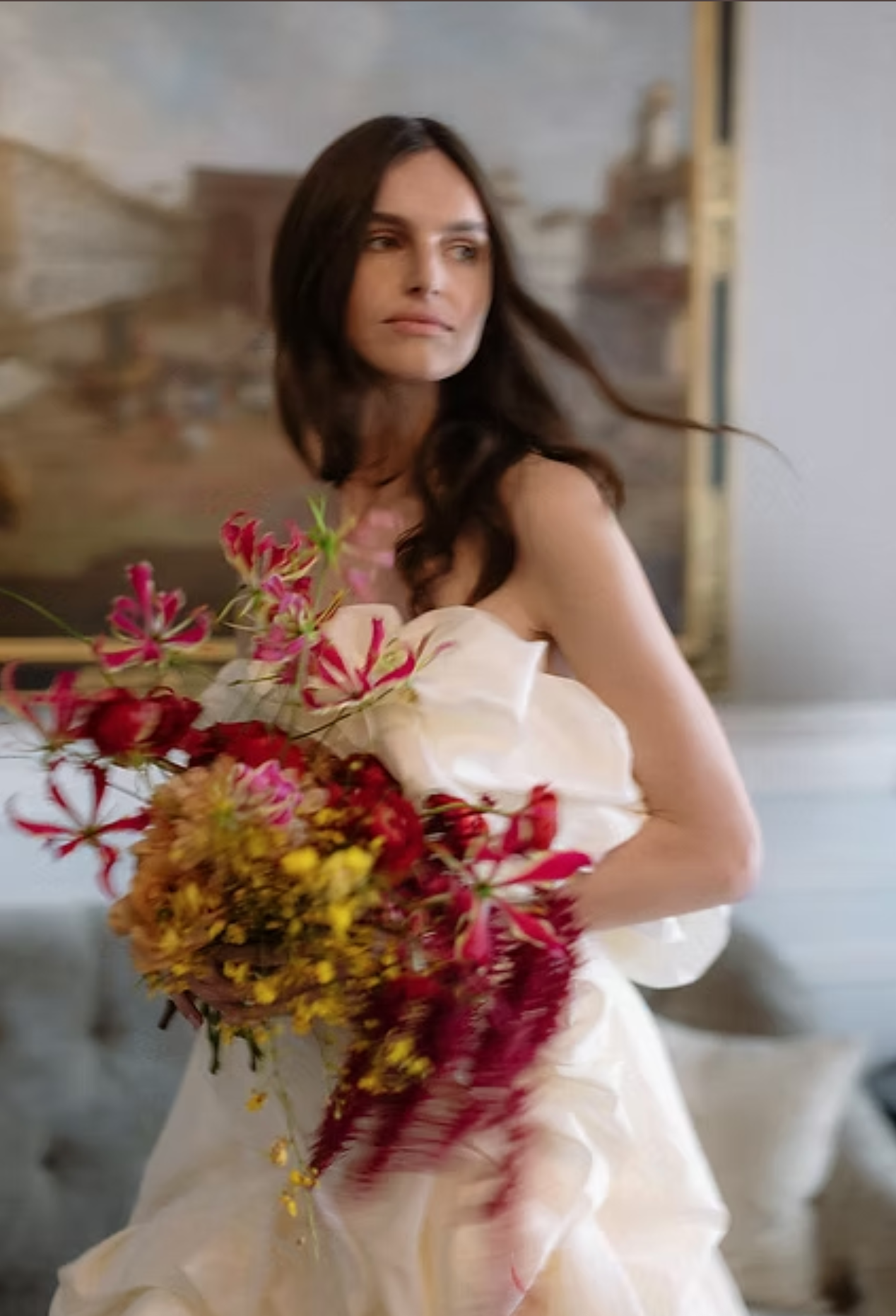 Dreamy bridal portrait featuring white gown and vibrant red and gold floral bouquet.