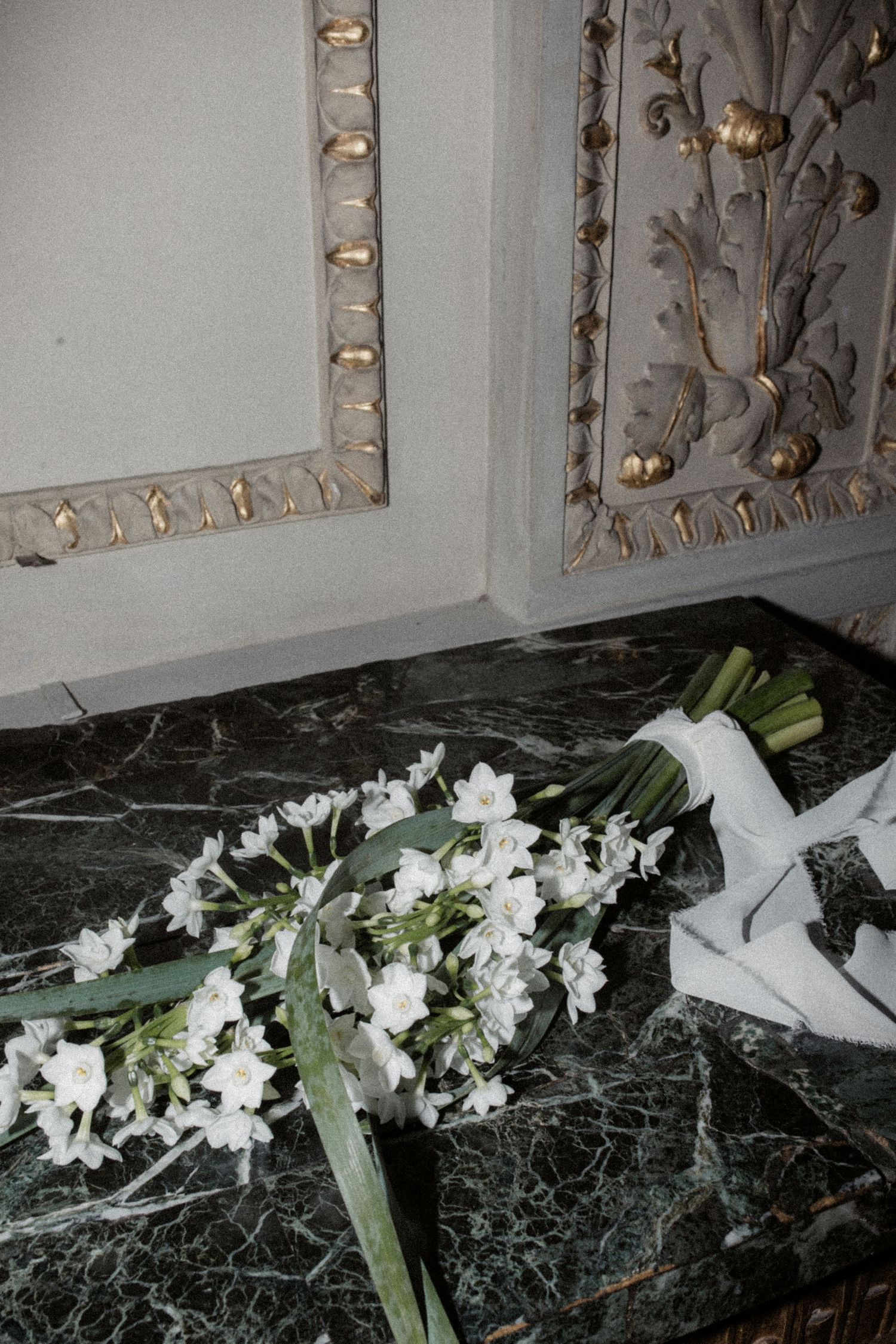 White paperwhite narcissus flowers arranged on black marble surface.