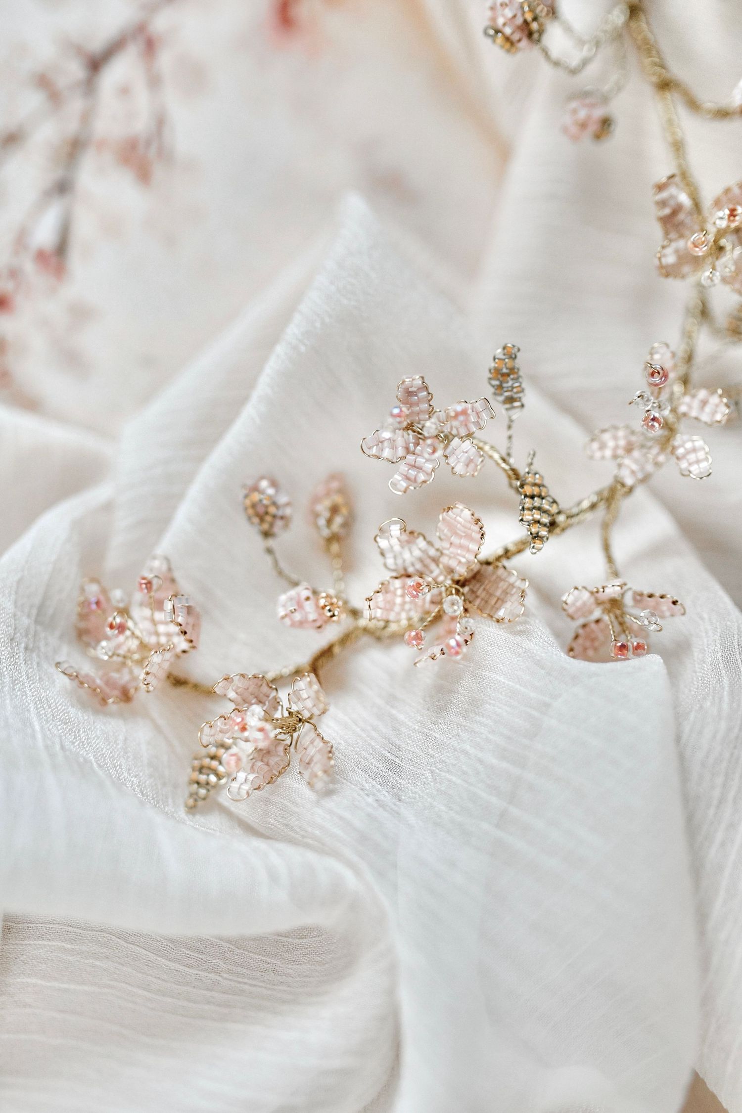 Intricate beaded floral details in rose gold shimmer against white fabric.