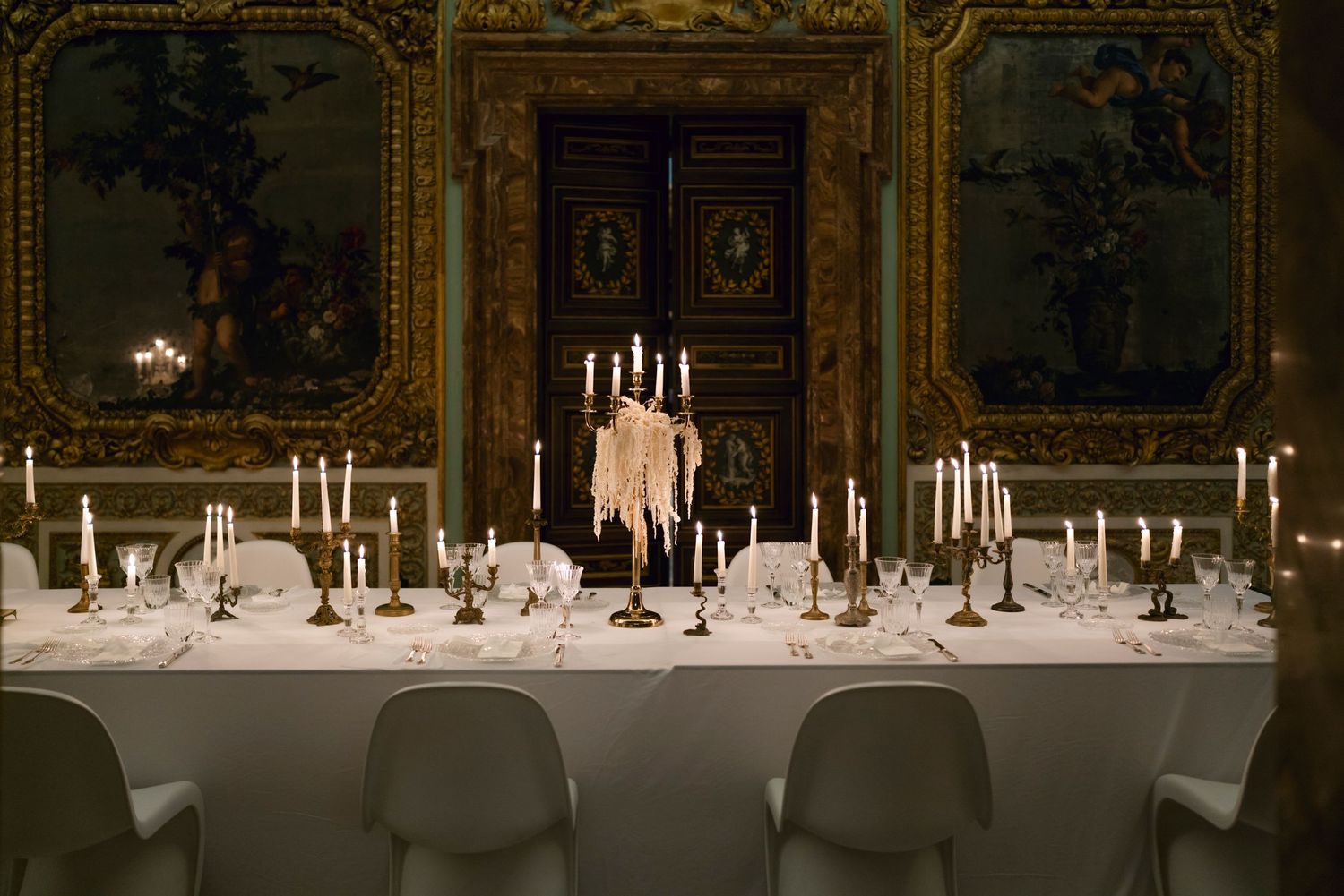 Formal dining table set with elegant candelabras and place settings in ornate gilded room.
