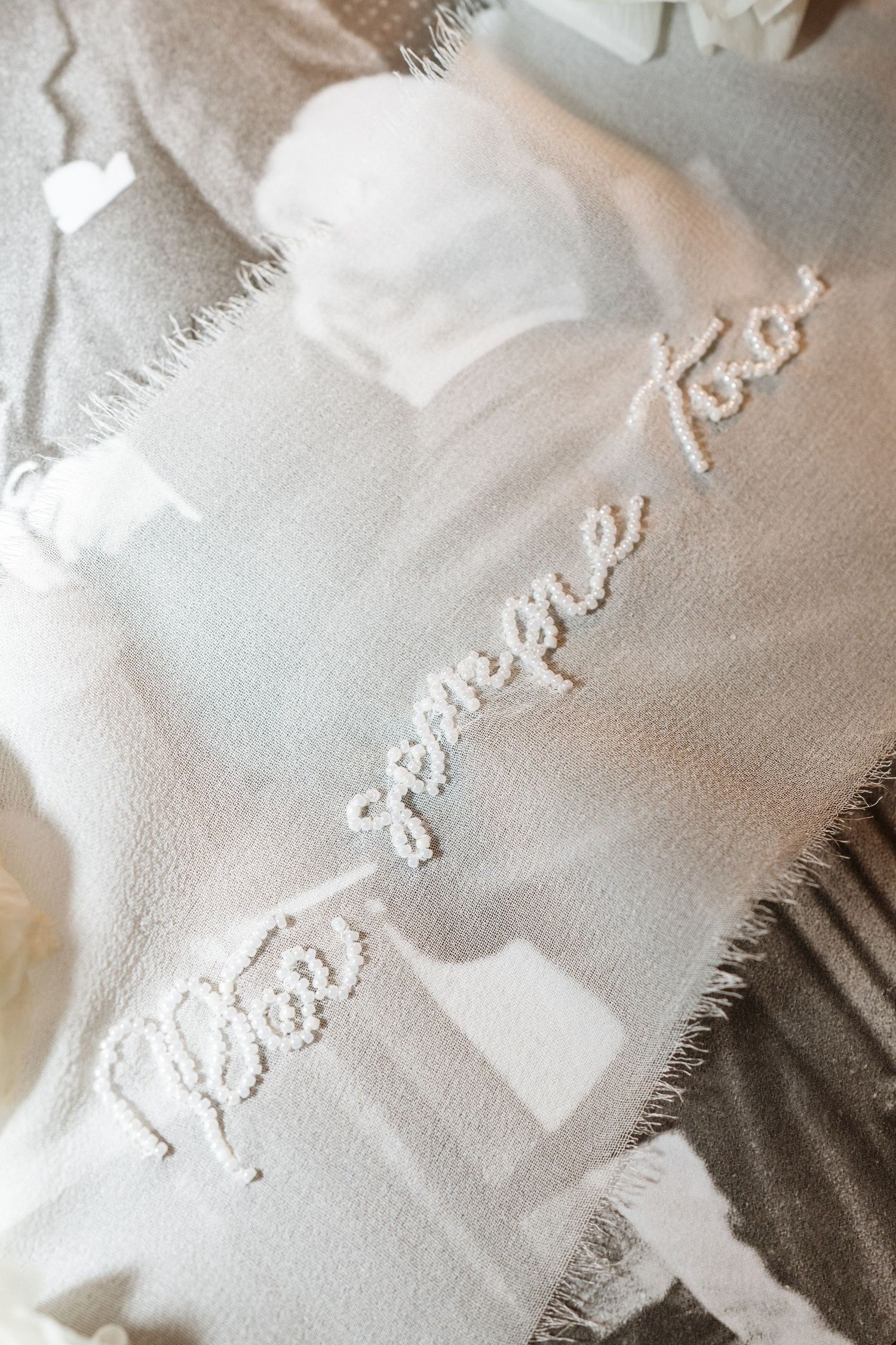 Close-up of white embroidered text on delicate fabric with soft lighting.